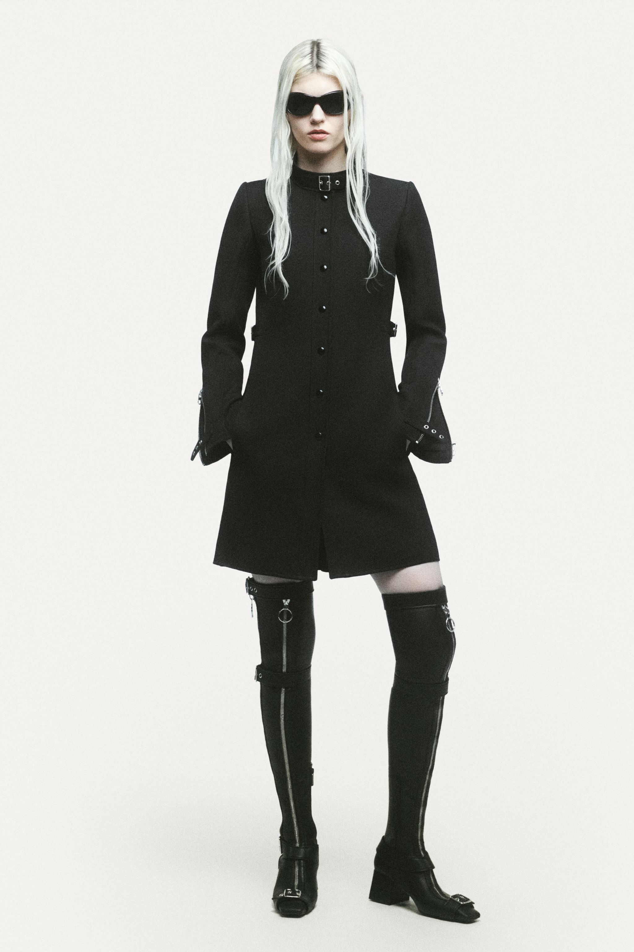 Elegant black dress with zipper details, stylishly paired with thigh-high boots and sunglasses for Courrèges.
