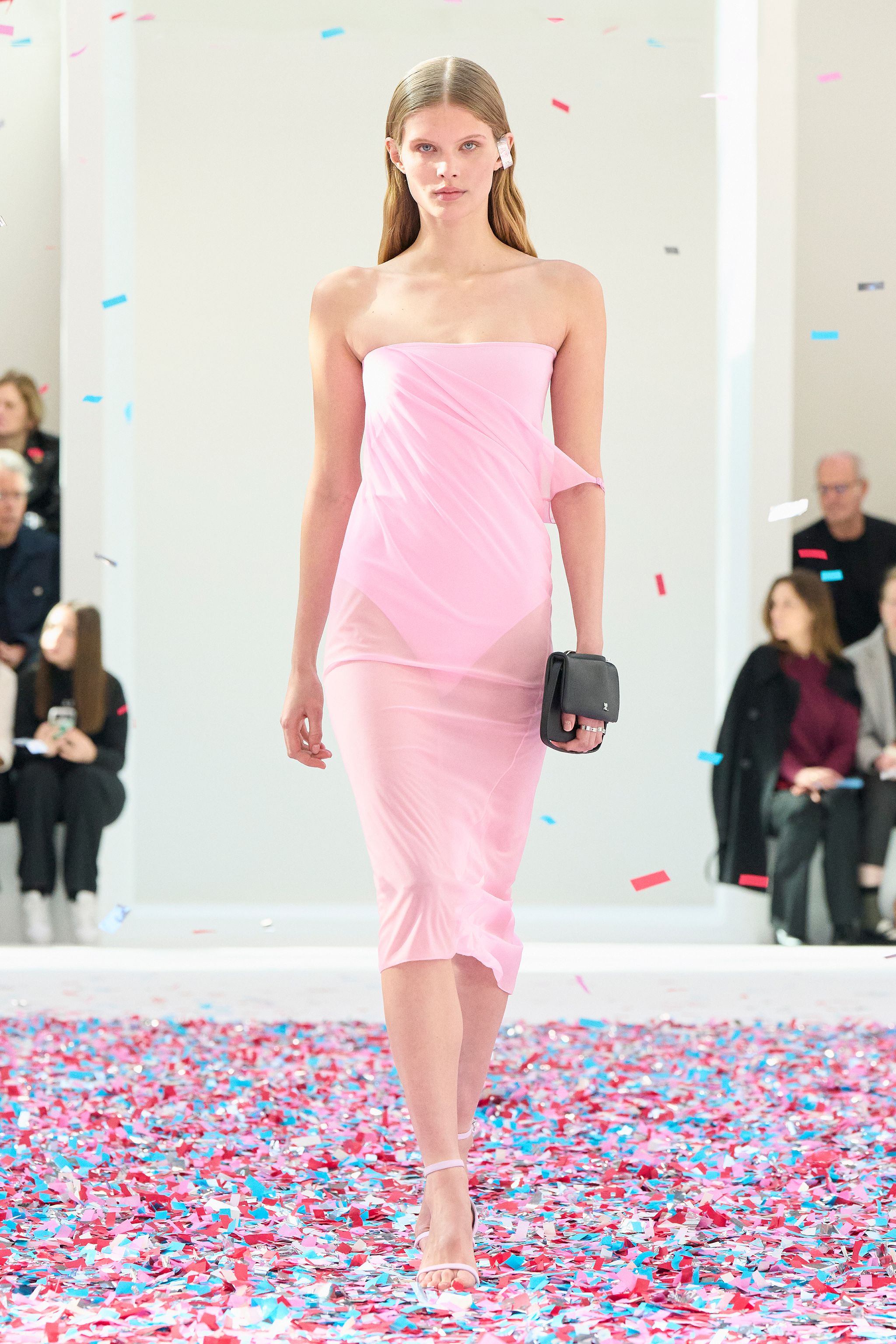 Elegant pink strapless dress by Courrèges on a runway with colorful confetti.