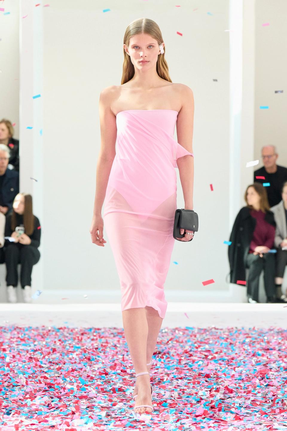 Elegant pink strapless dress by Courrèges on a runway with colorful confetti.