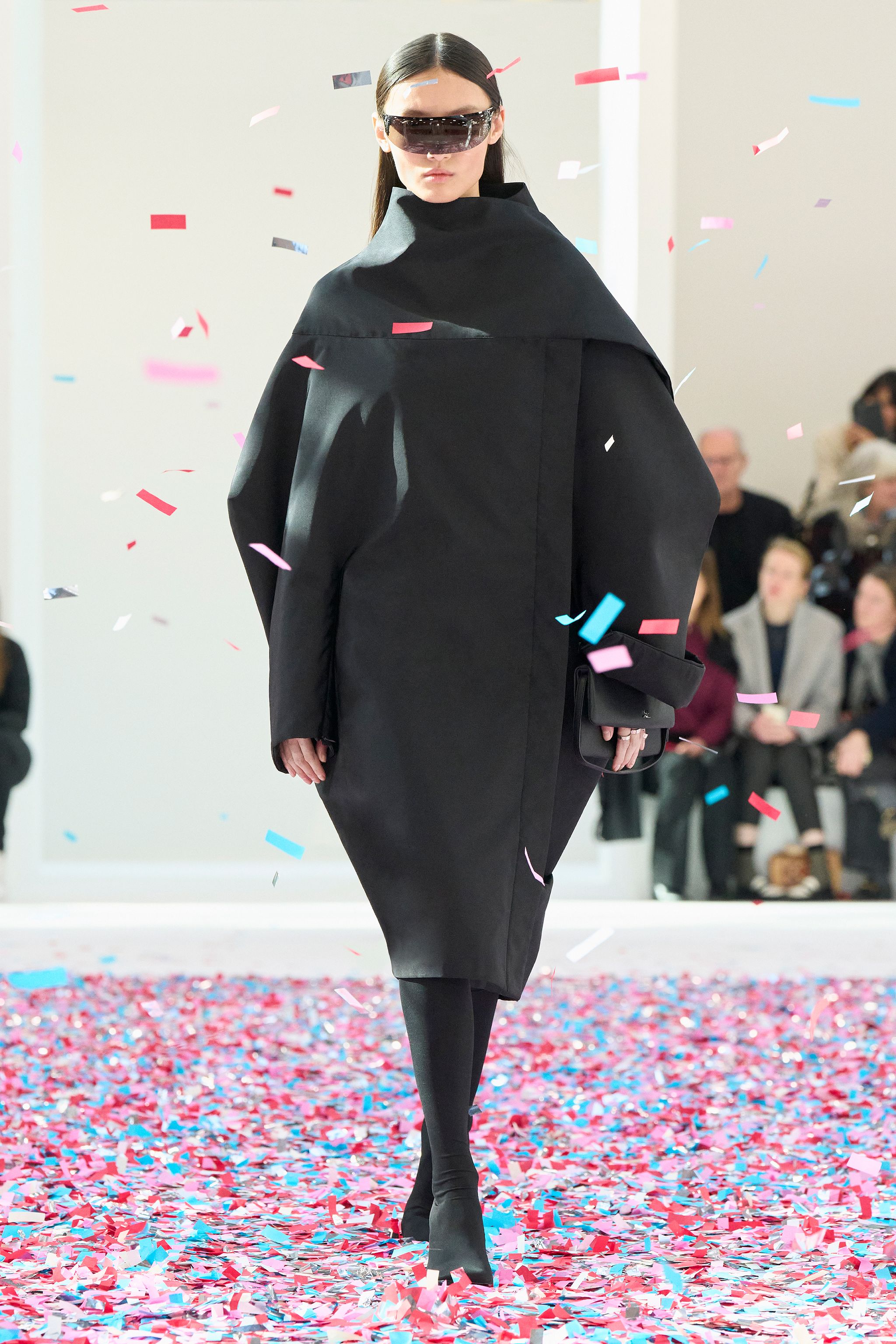 Elegant female model in a chic, patterned dress walking on a colorful runway wearing Courrèges.