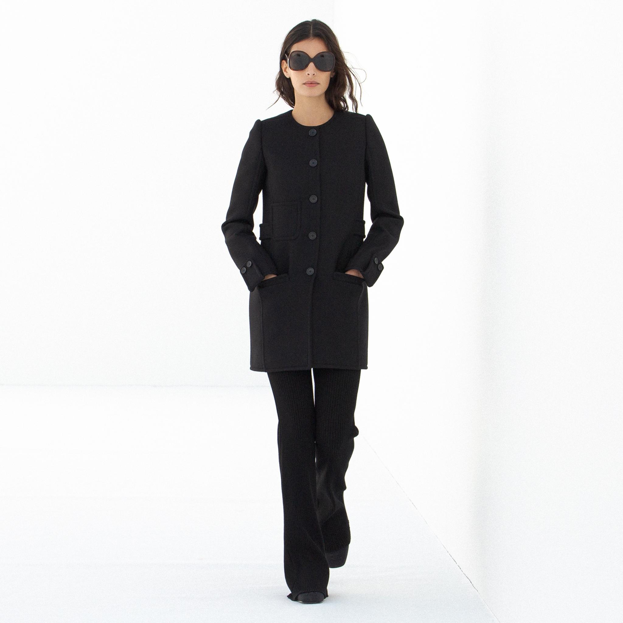 Manteau noir élégant et chic avec boutons larges, vêtement de la marque Courrèges.