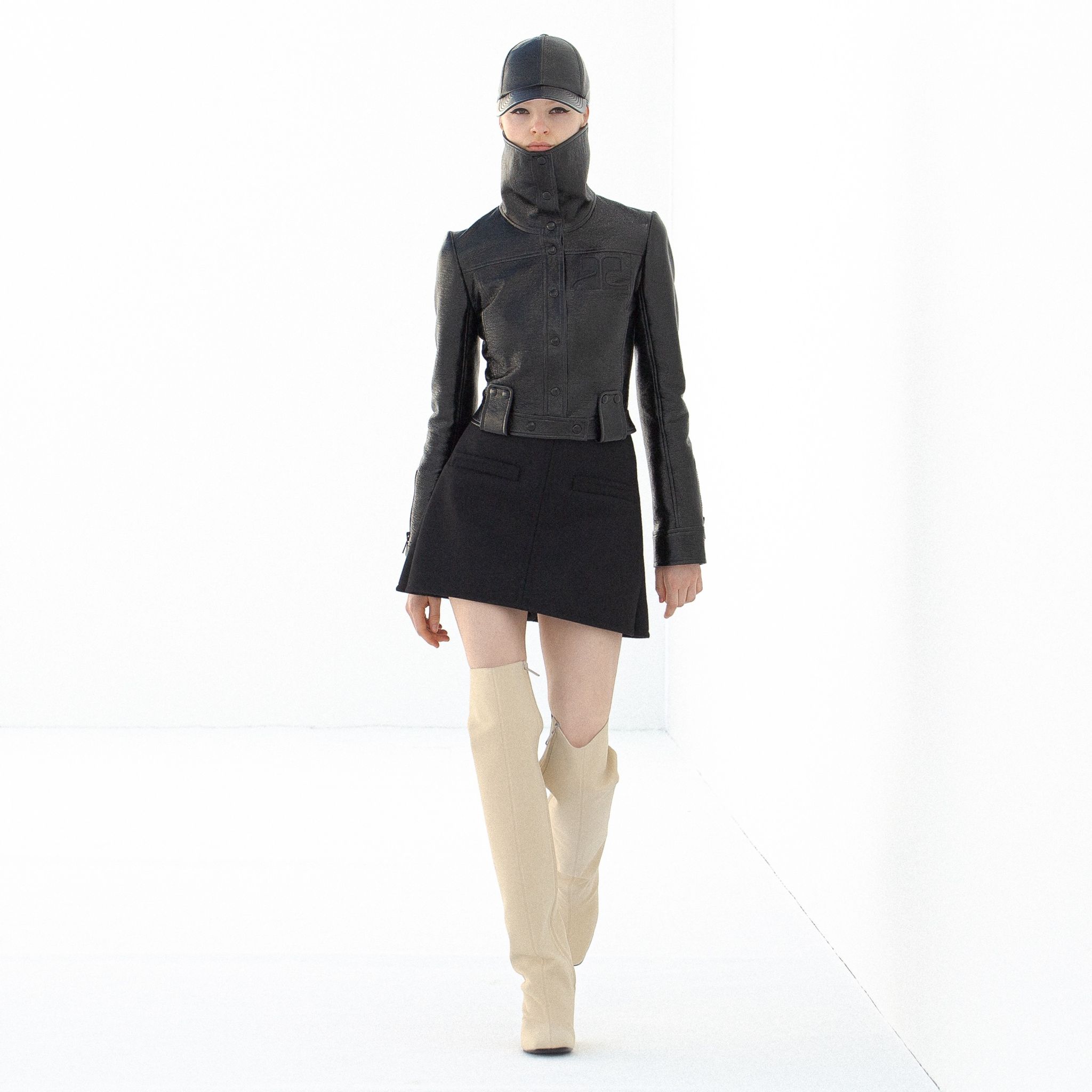 Elegant black leather jacket and off-white high boots, showcased on a runway for Courrèges.