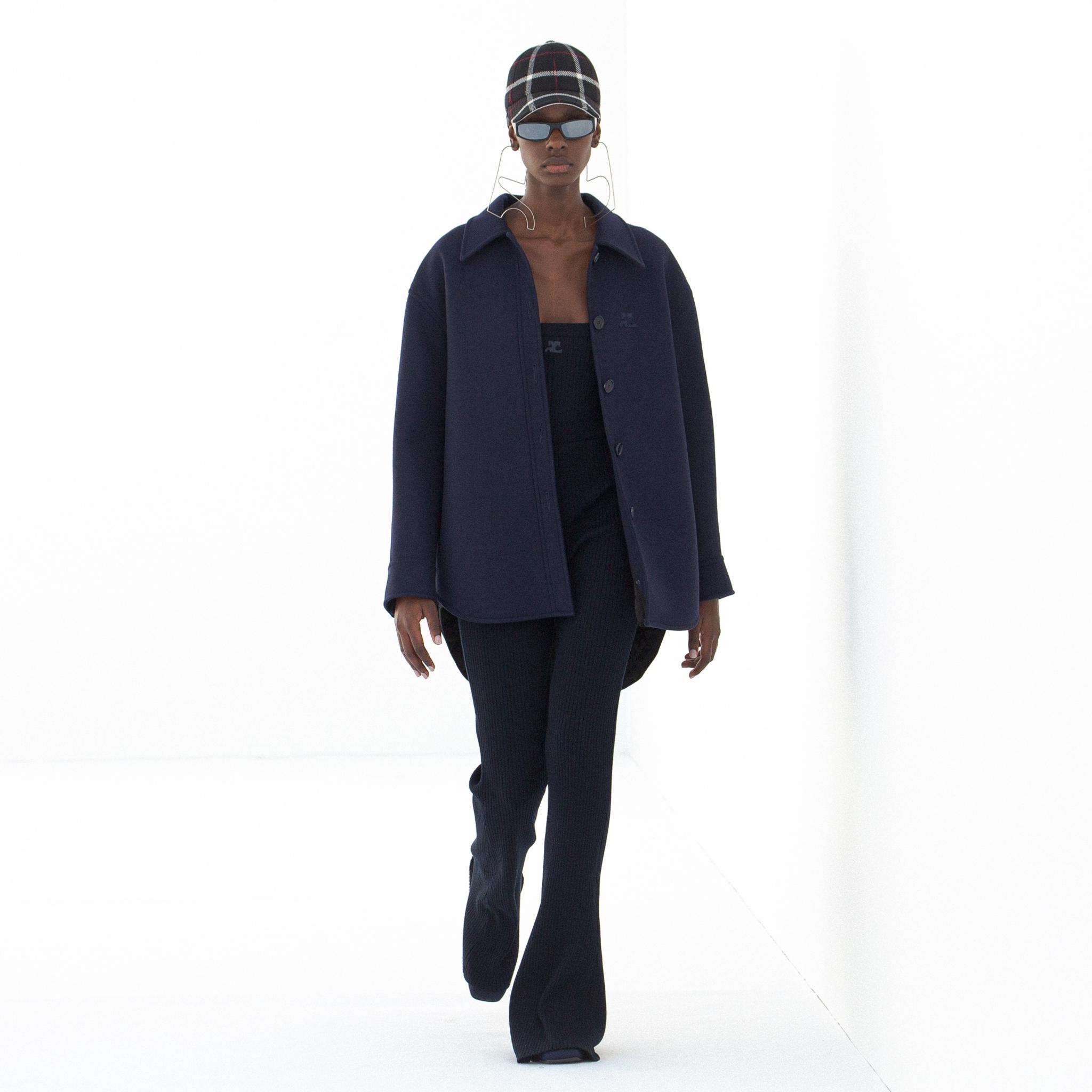 Manteau et pull bleu marine élégants, accessoirisés de lunettes de soleil stylées pour Courrèges.