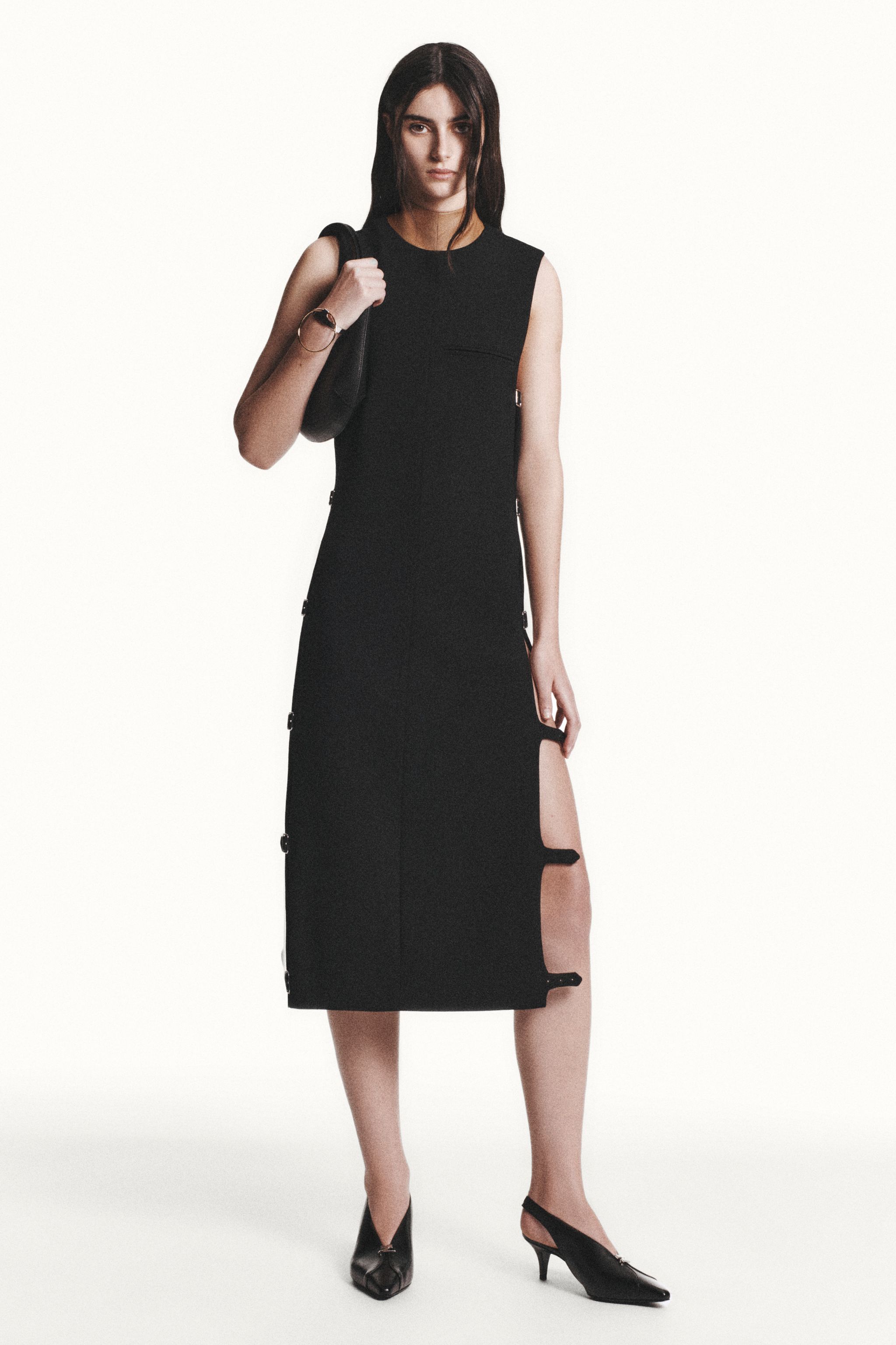 Elegant black dress with side zippers and thigh-high slit, styled for Courrèges fashion.
