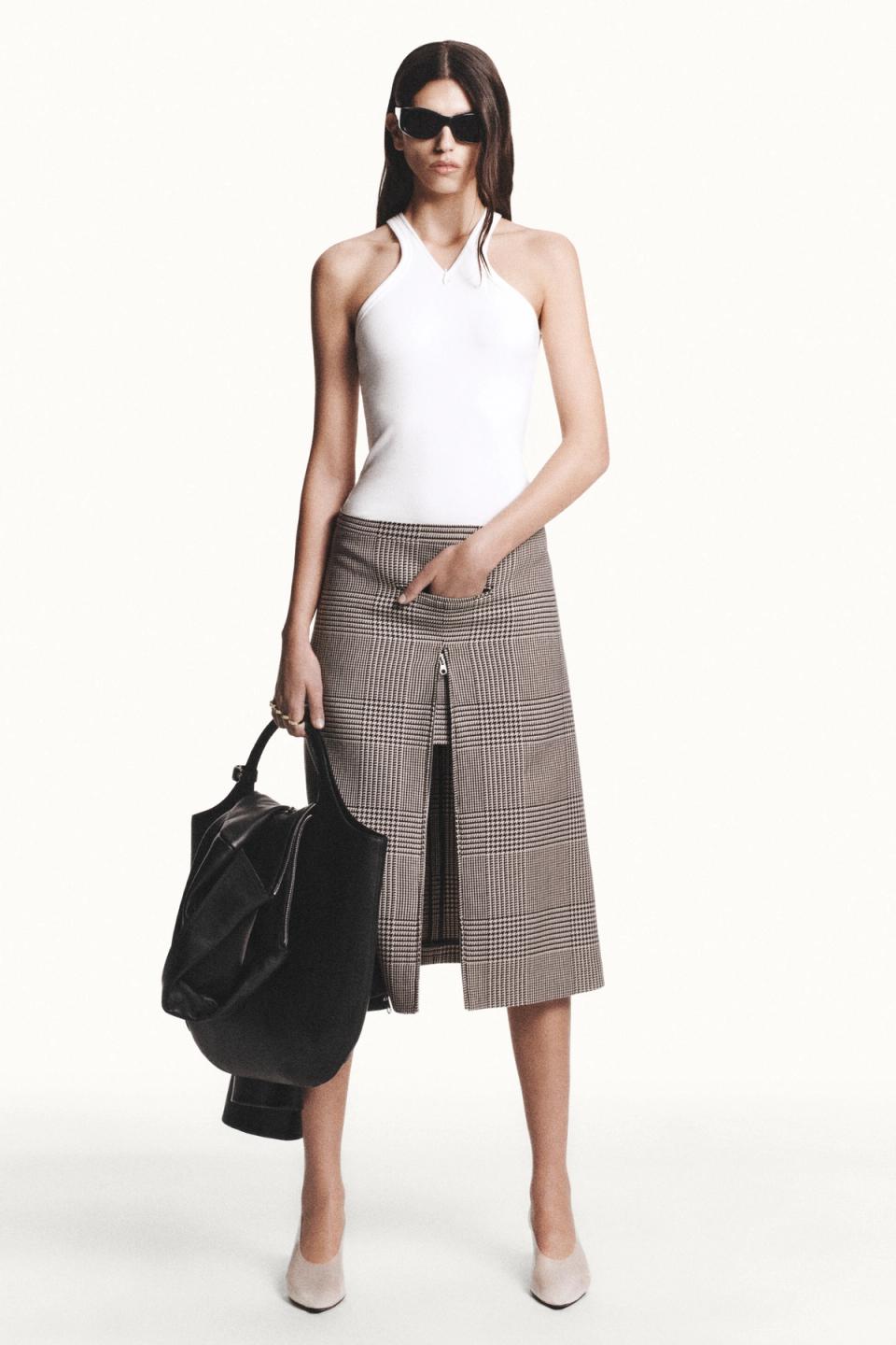 Elegant female model showcasing Courrèges fashion with chic skirt, white top, and sunglasses.