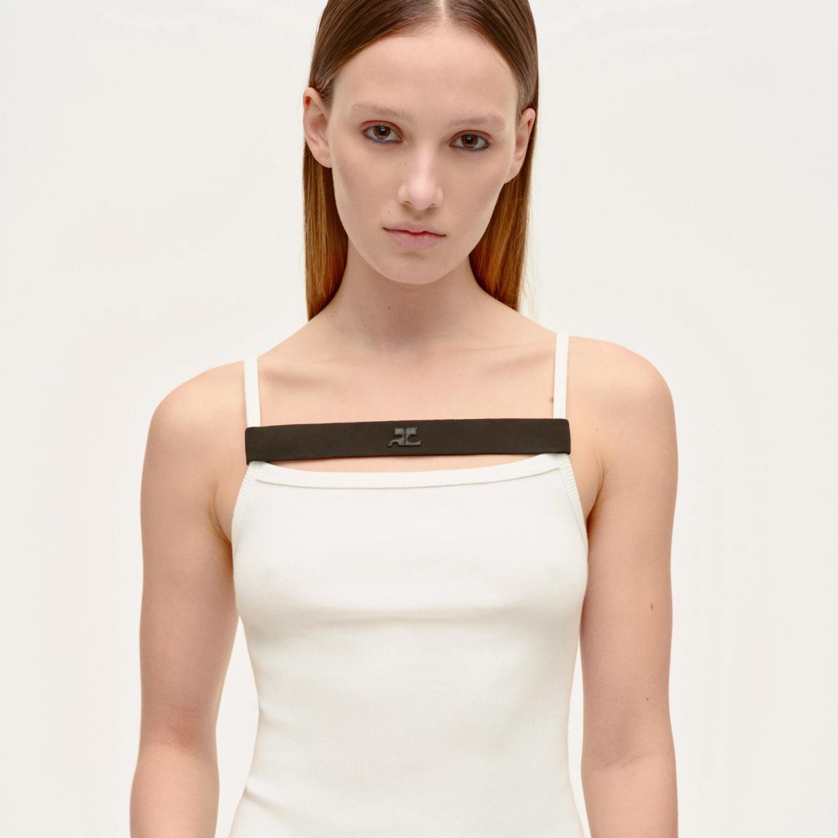 Elegant model wearing Courrèges fashion, white top with black strap, minimalist style.