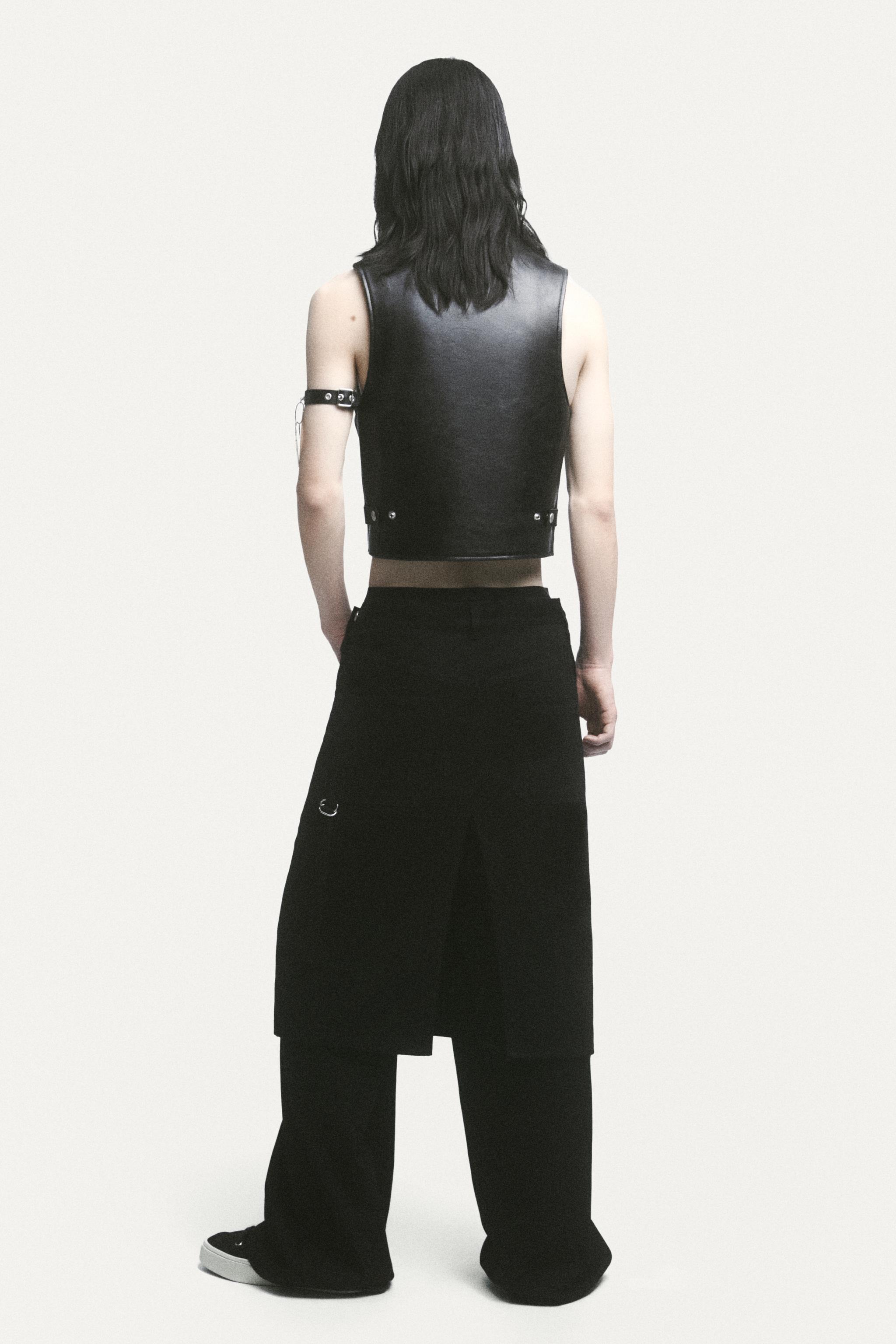 Model wearing a chic black leather vest and wide-leg black pants, Courrèges fashion look.