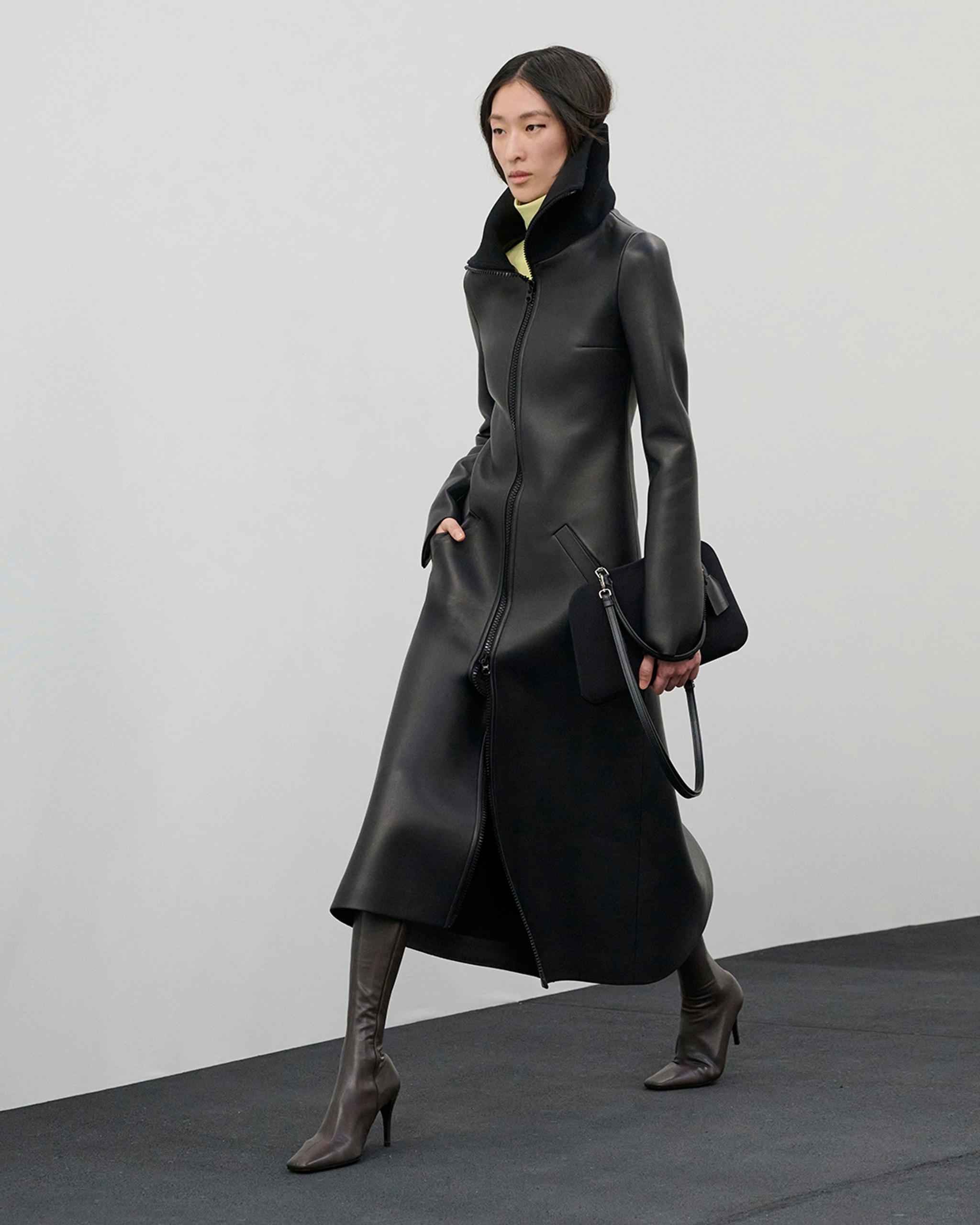 Elegant black leather coat by Courrèges, styled with high boots for a chic fashion look.