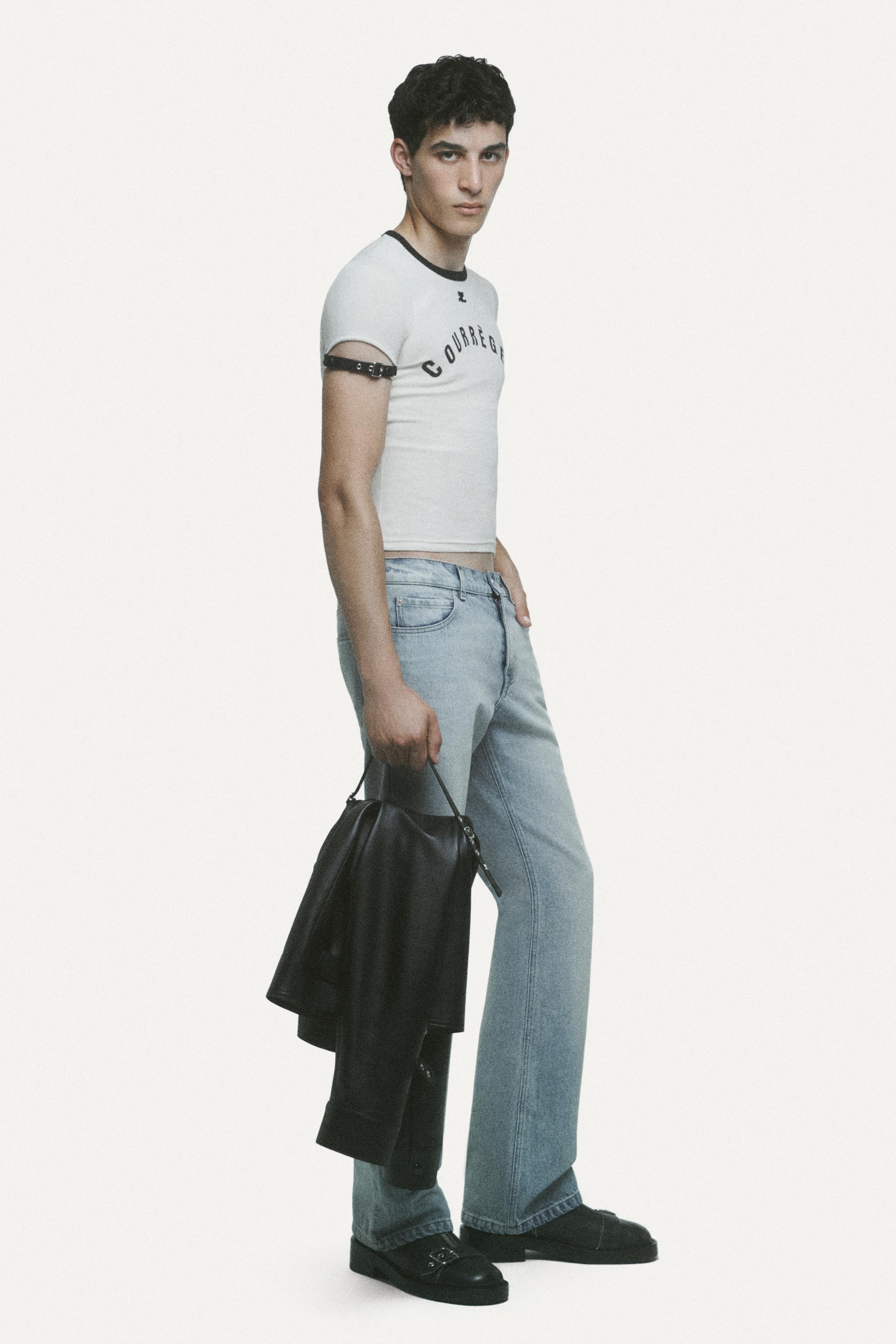 Elegant model wearing Courrèges casual fashion with a graphic top, jeans, and accessories.