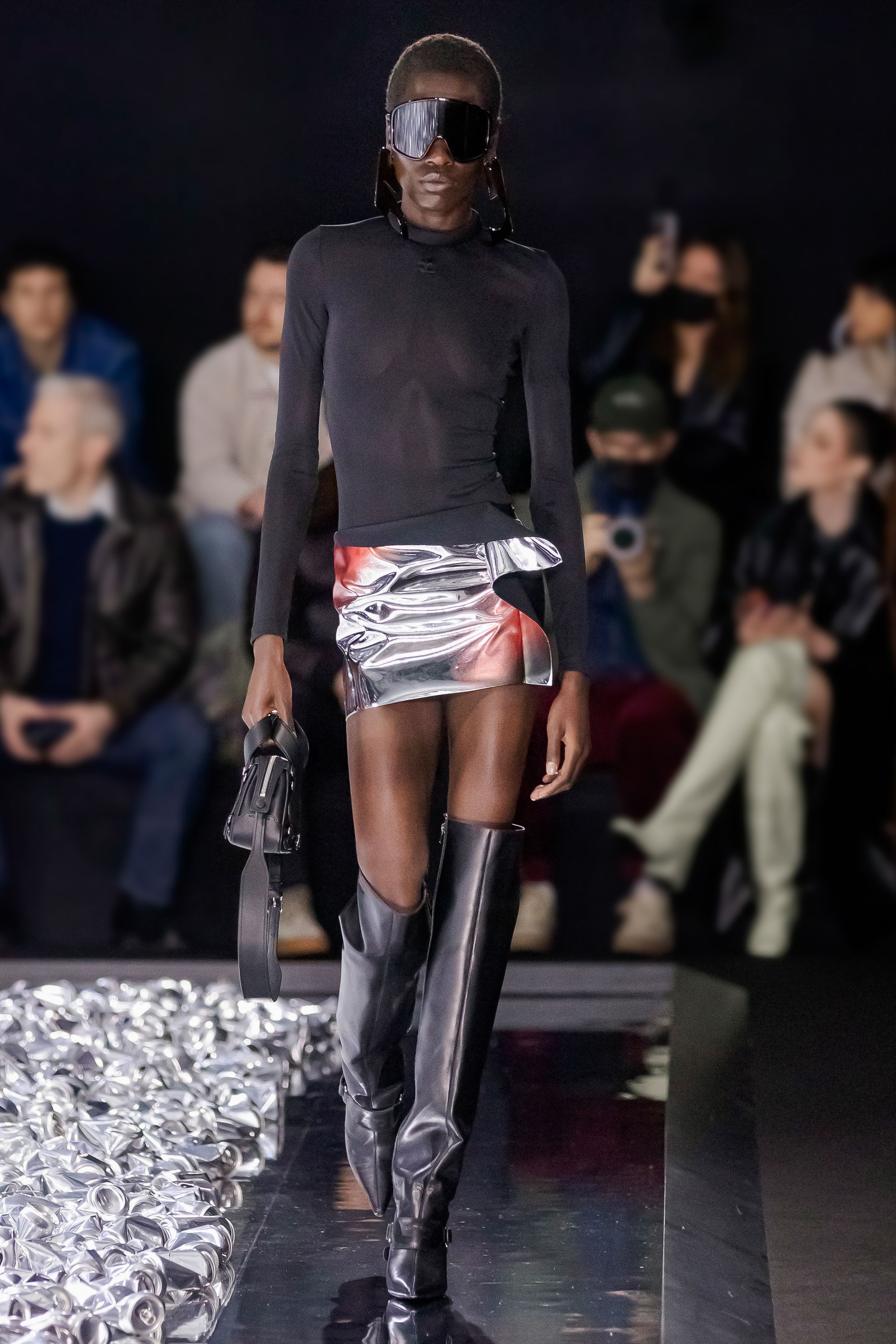 Elegant Courrèges runway fashion featuring a sleek black top, metallic skirt, and thigh-high boots.
