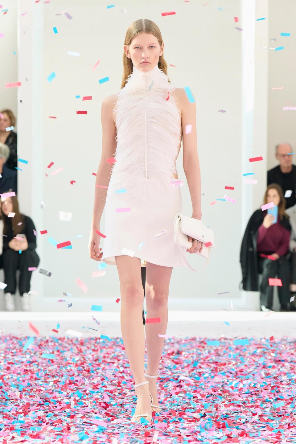 Elegant white feathered dress runway shot with colorful confetti for Courrèges fashion brand.
