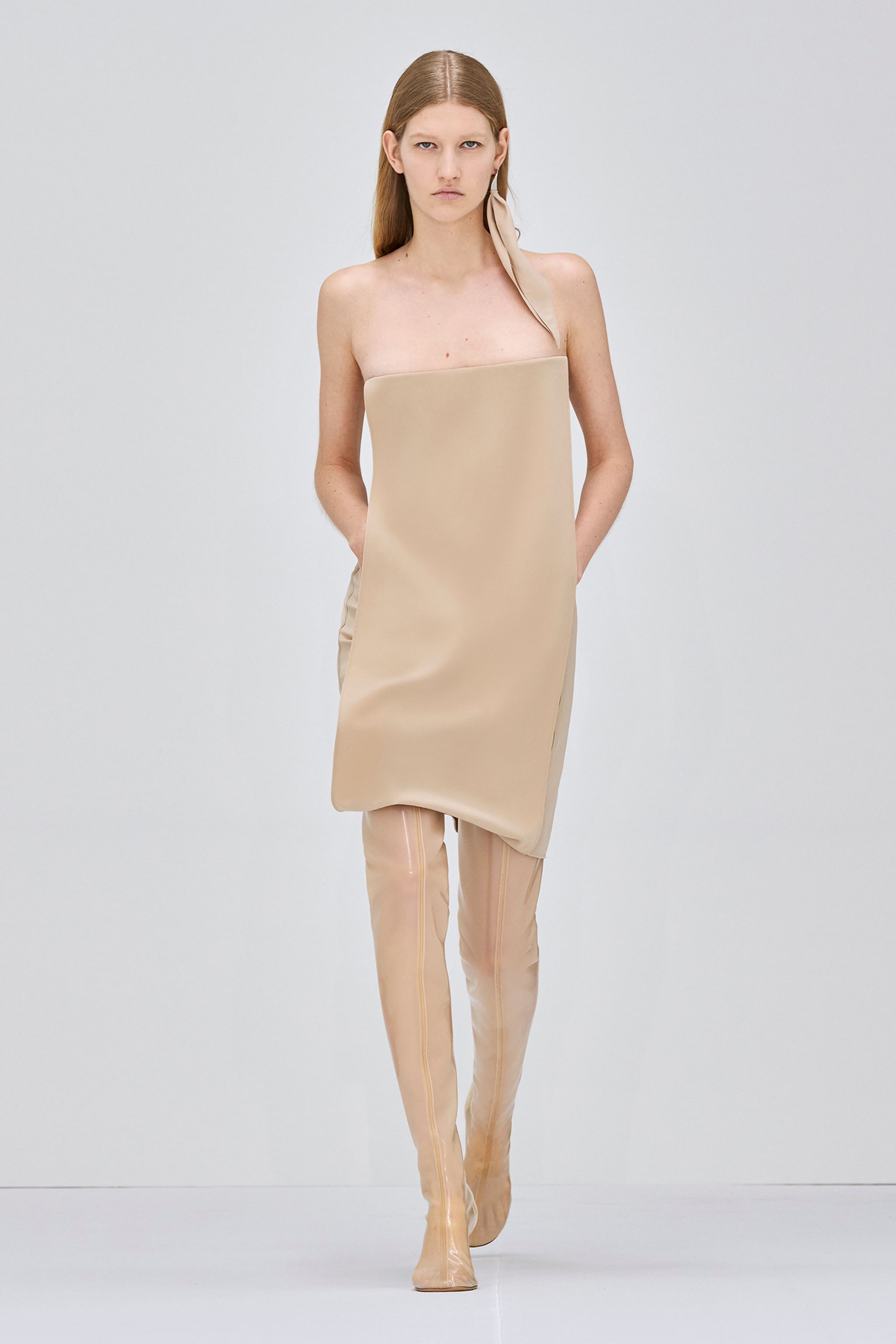 Elegant beige sleeveless dress by Courrèges displayed on runway model in an ecommerce context.