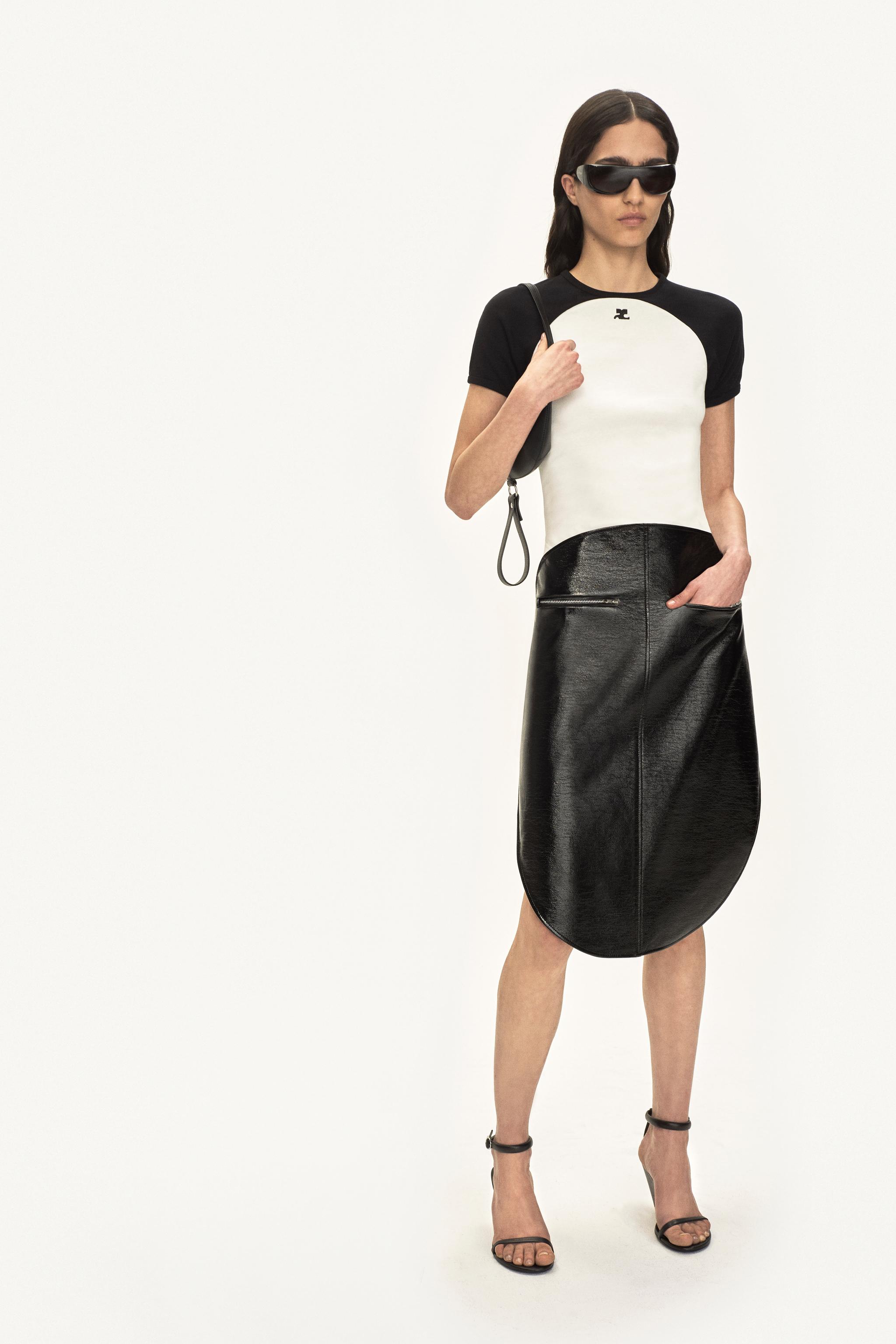 Modèle élégant présentant une tenue Courrèges noire et blanche pour site de commerce en ligne.