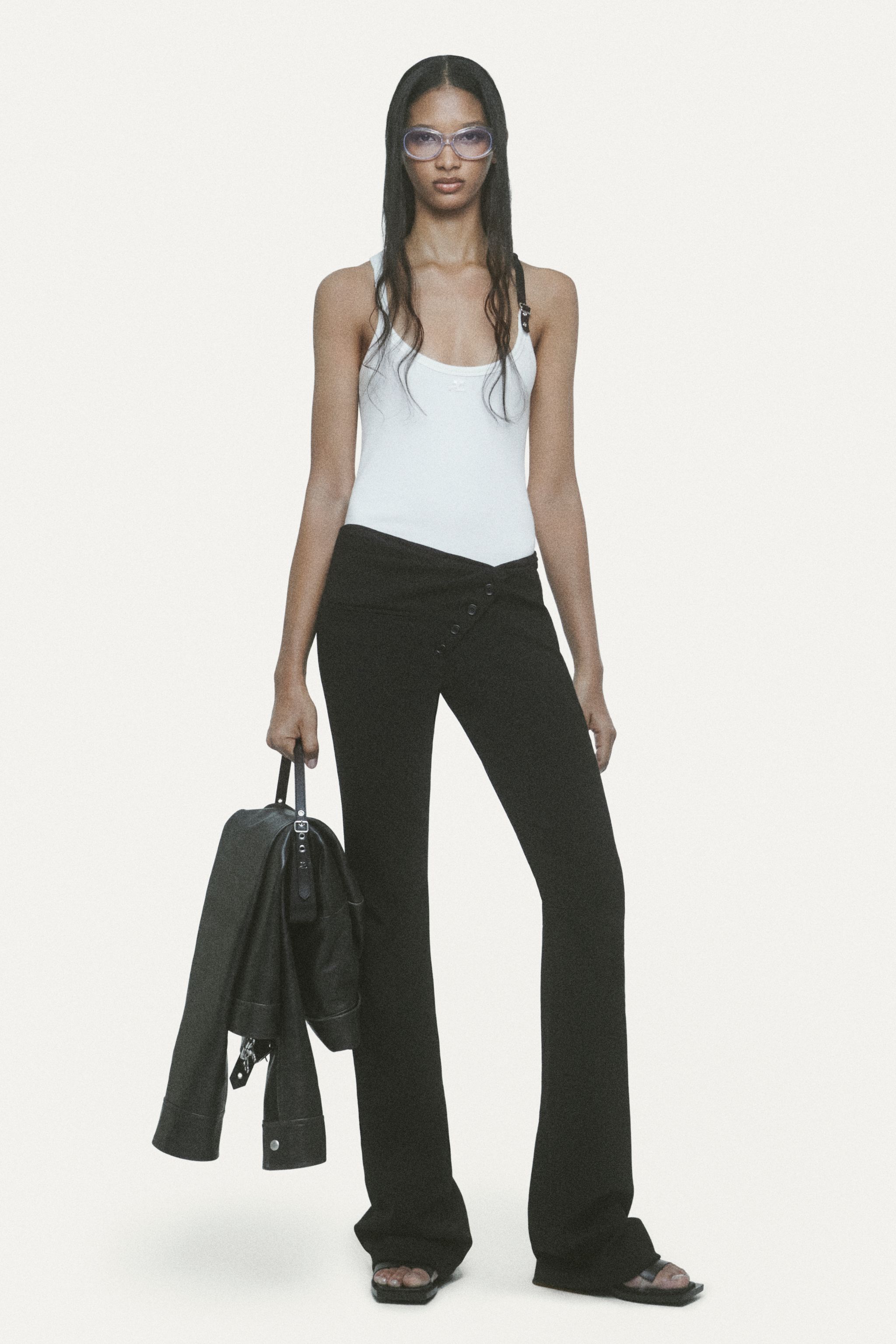 Elegant model in Courrèges fashion brand casual outfit, carrying a black bag and wearing sunglasses.
