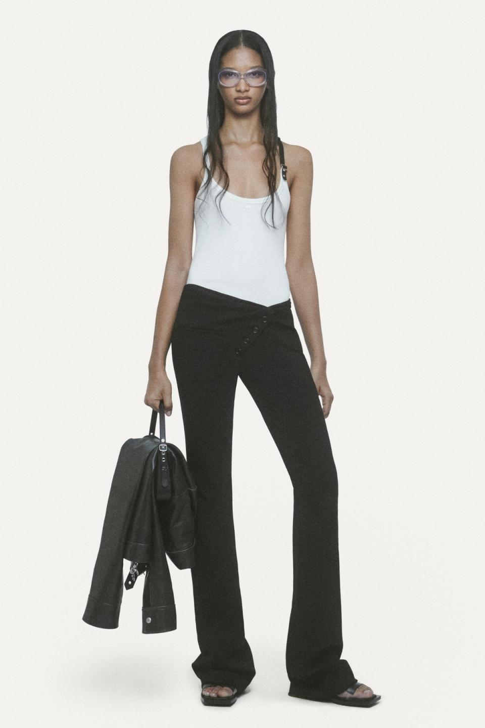 Elegant model in Courrèges fashion brand casual outfit, carrying a black bag and wearing sunglasses.