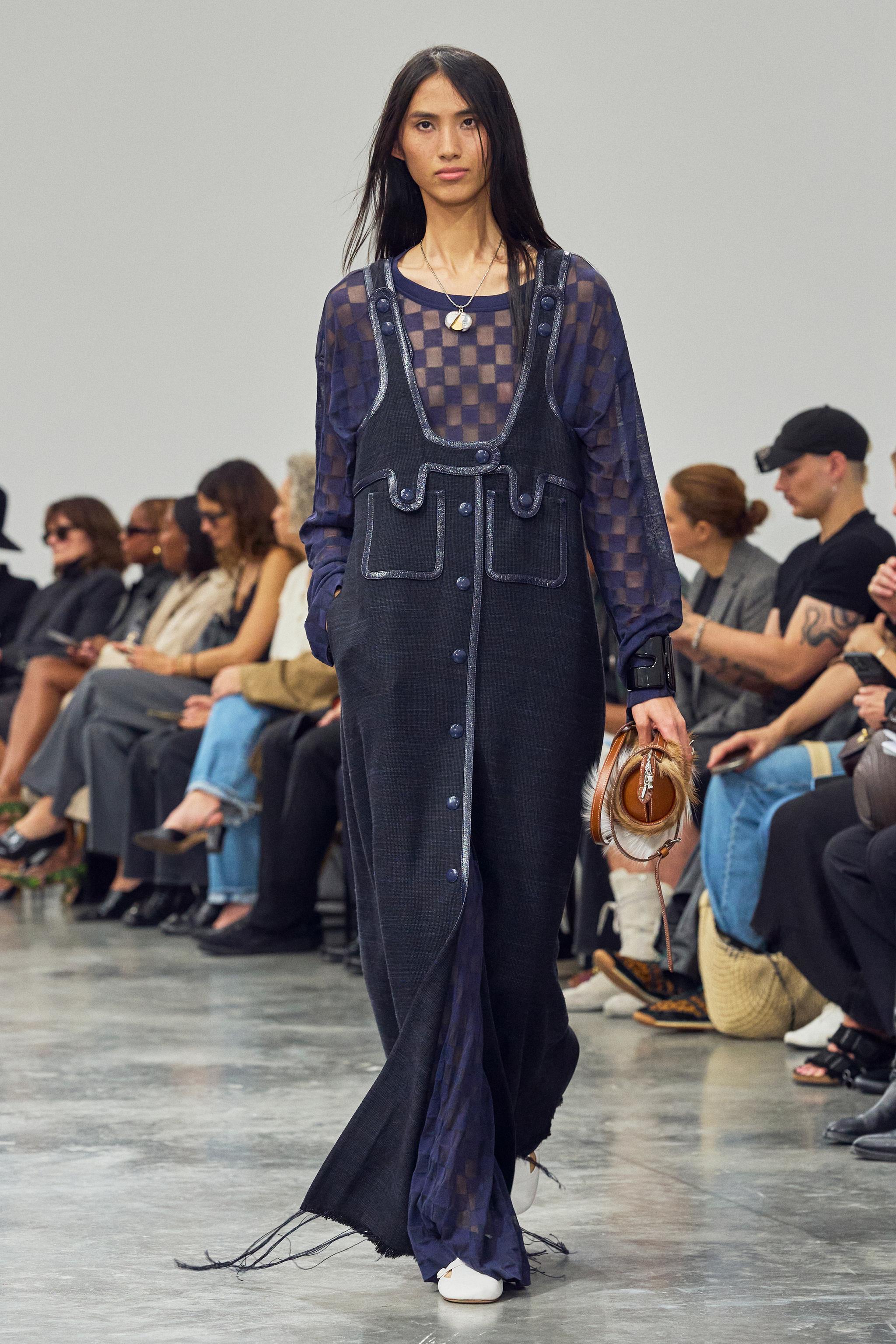 Elegant fashion runway model showcasing Courrèges denim overalls and layered outfit.