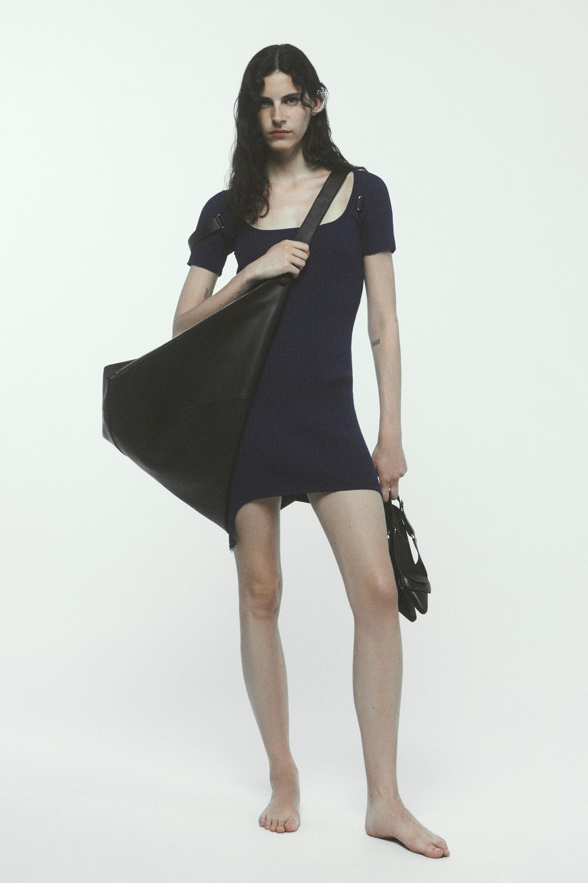 Elegant model wearing a navy dress with black accessories, showcasing Courrèges fashion.