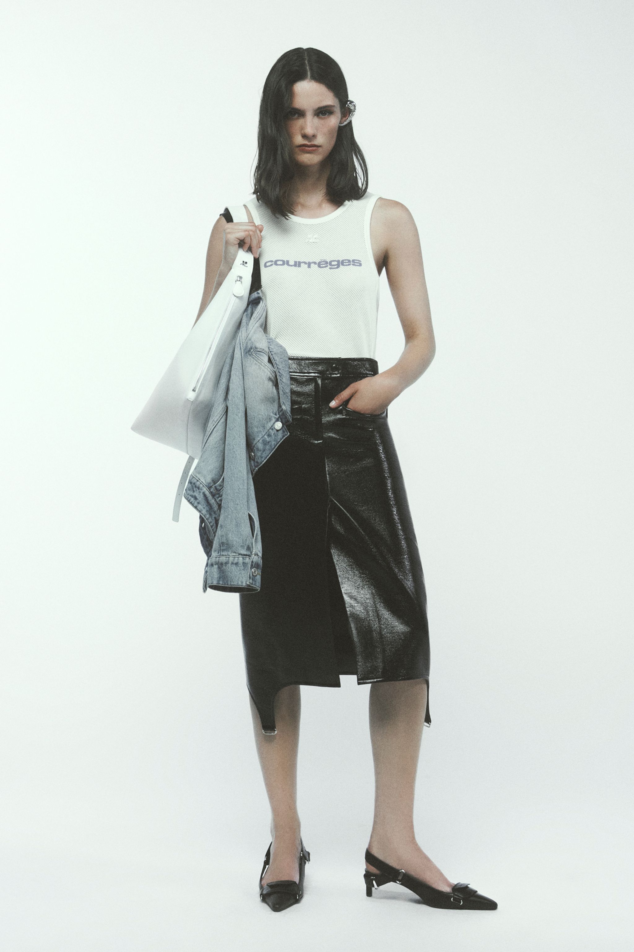 Elegant fashion model showcasing Courrèges chic tank top, leather skirt, and accessories.