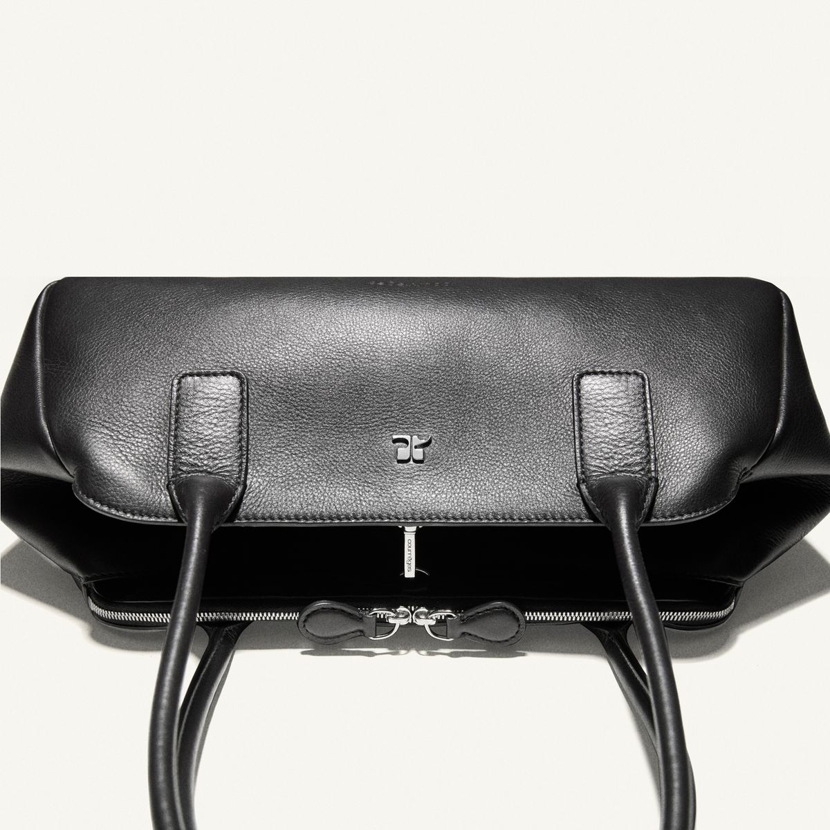 Elegant black leather handbag showcasing Courrèges’ minimalist and modern fashion style.