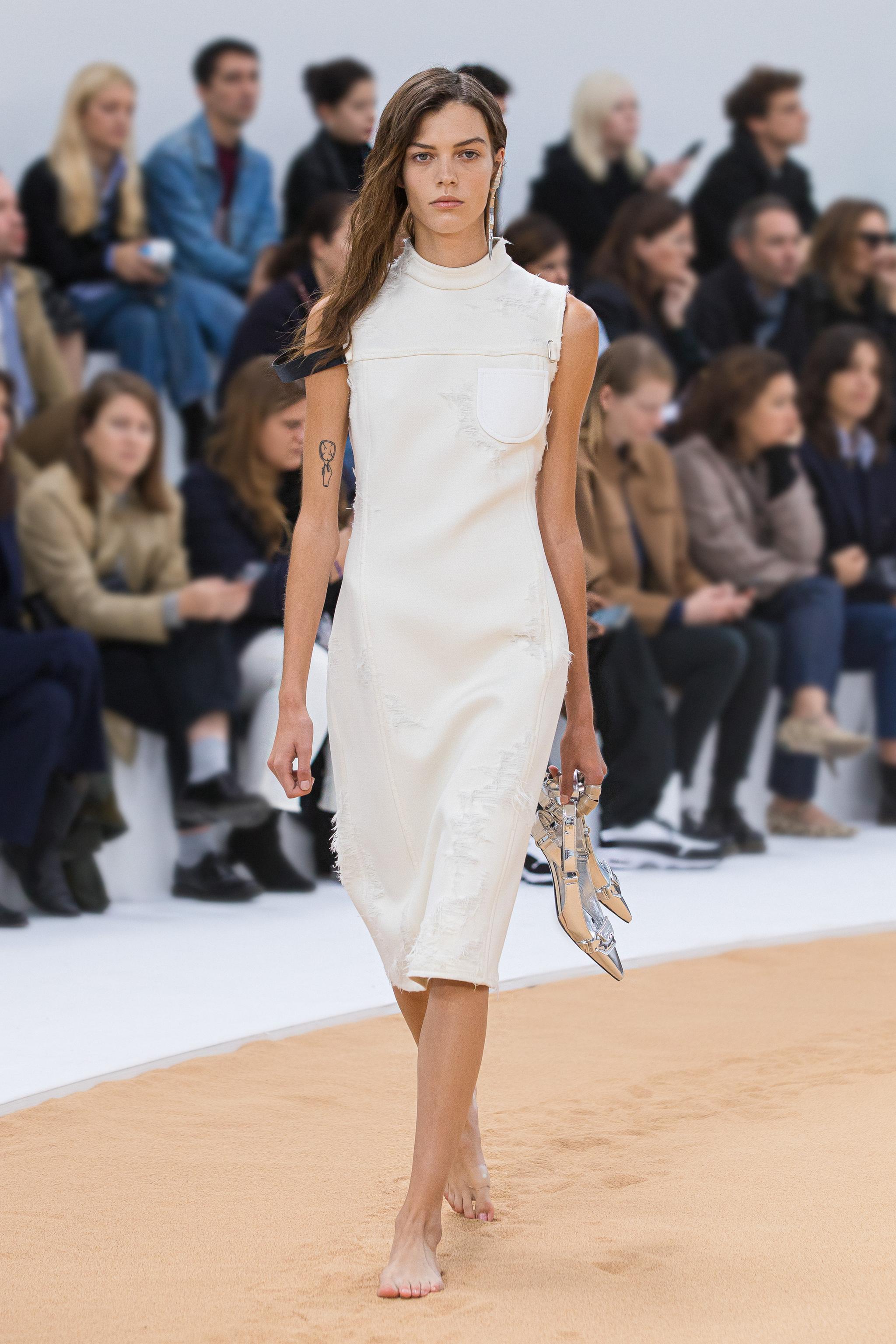 Modèle élégant portant une robe Courrèges chic sur un défilé de mode pour un site e-commerce.