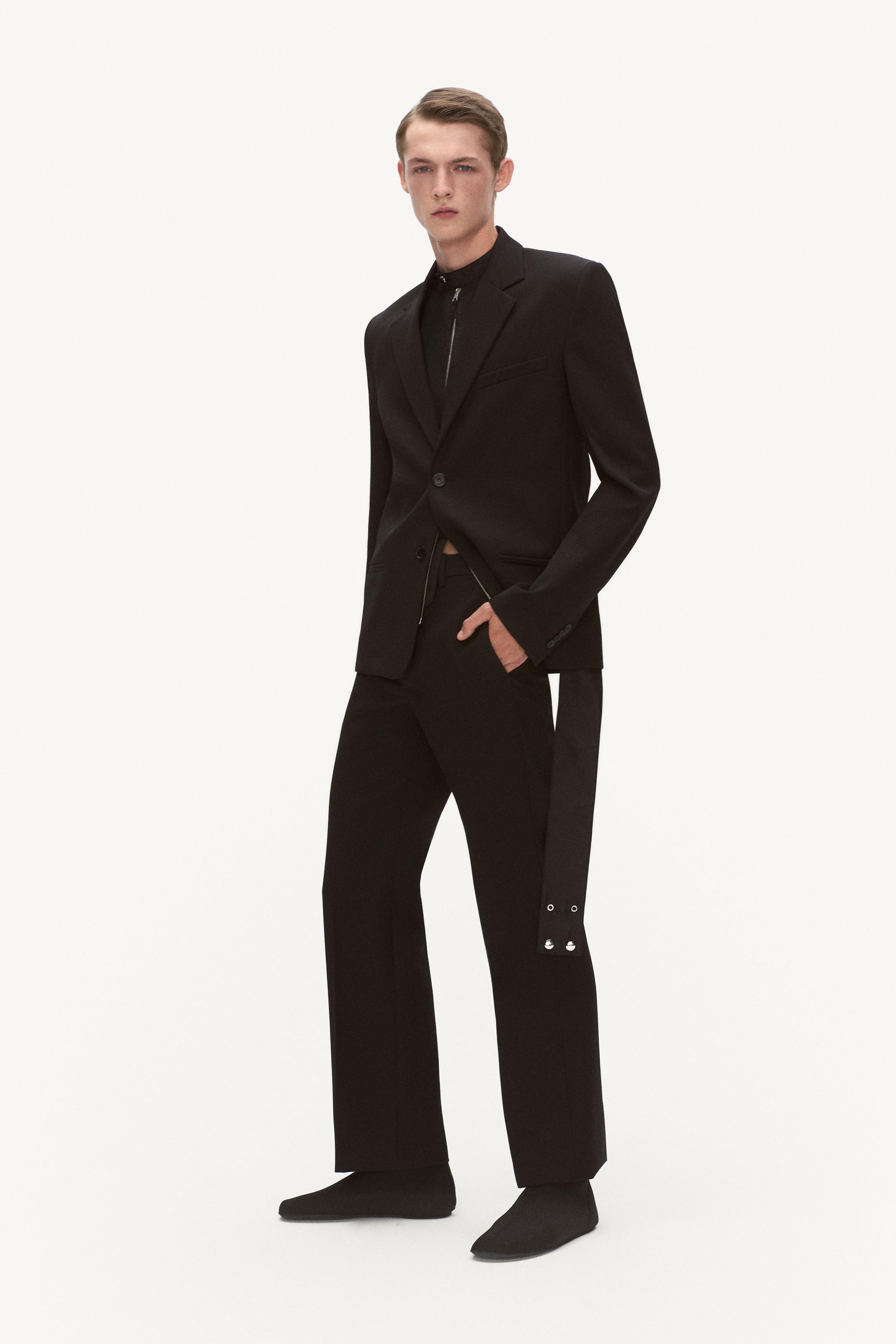 Elegant male model in black tailored suit, showcasing Courrèges fashion for an e-commerce site.