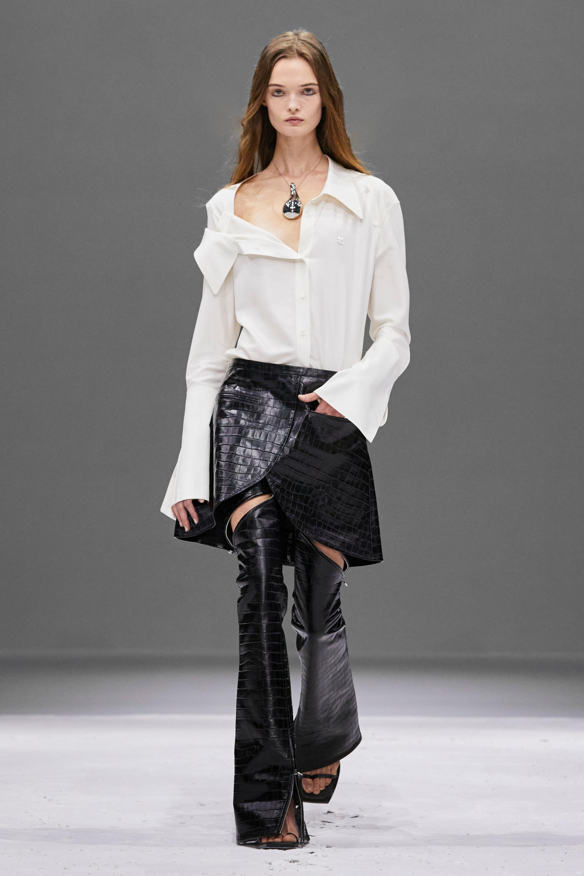 Elegant white shirt paired with black crocodile-effect leather skirt and over-the-knee boots, Courrèges fashion.