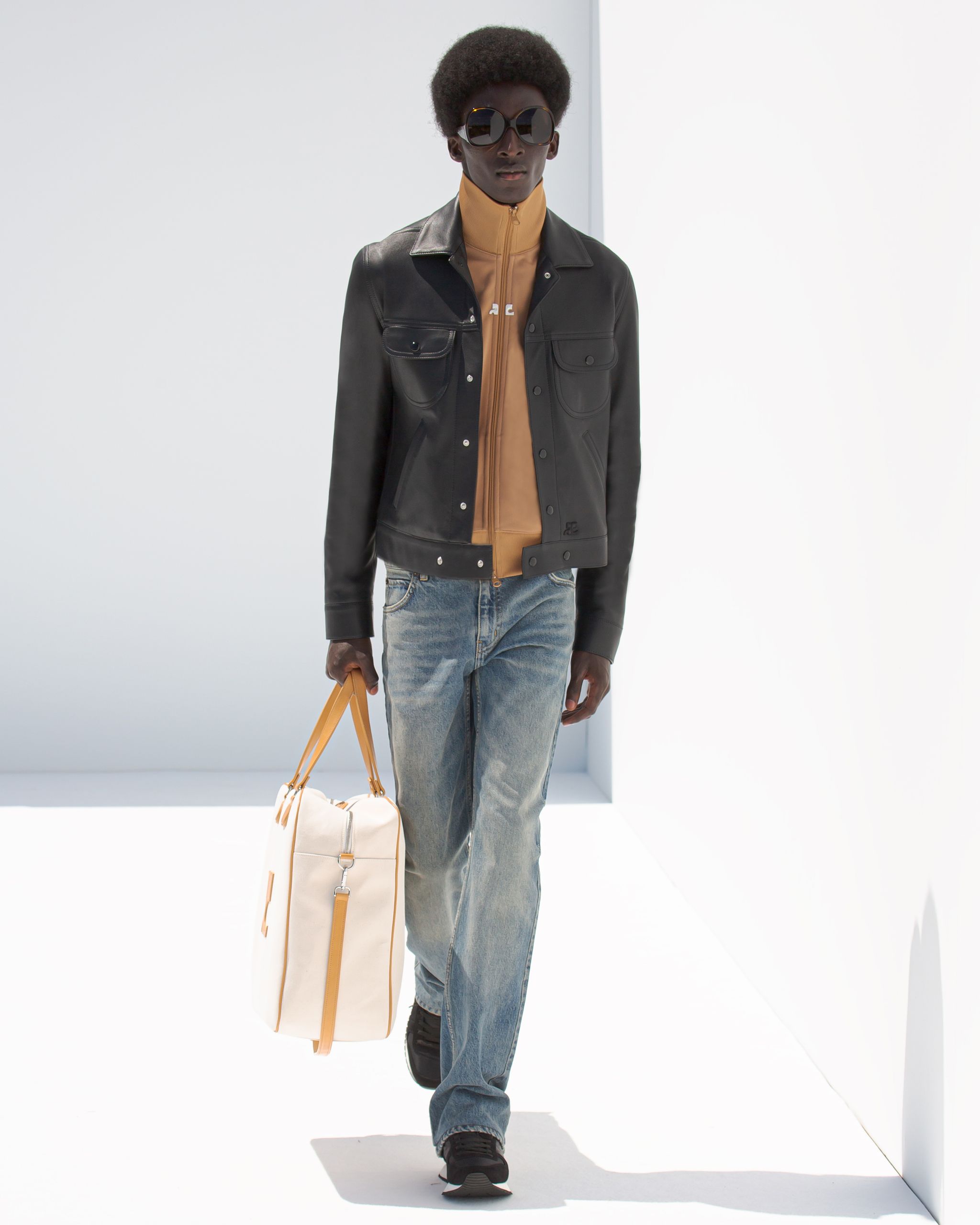 Model wearing stylish leather jacket, beige zip-up, and casual jeans for Courrèges fashion.
