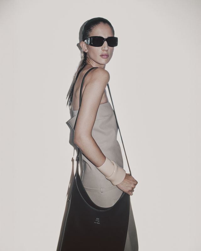 Modèle élégant portant des accessoires Courrèges, des lunettes de soleil modernes, et un sac tote.