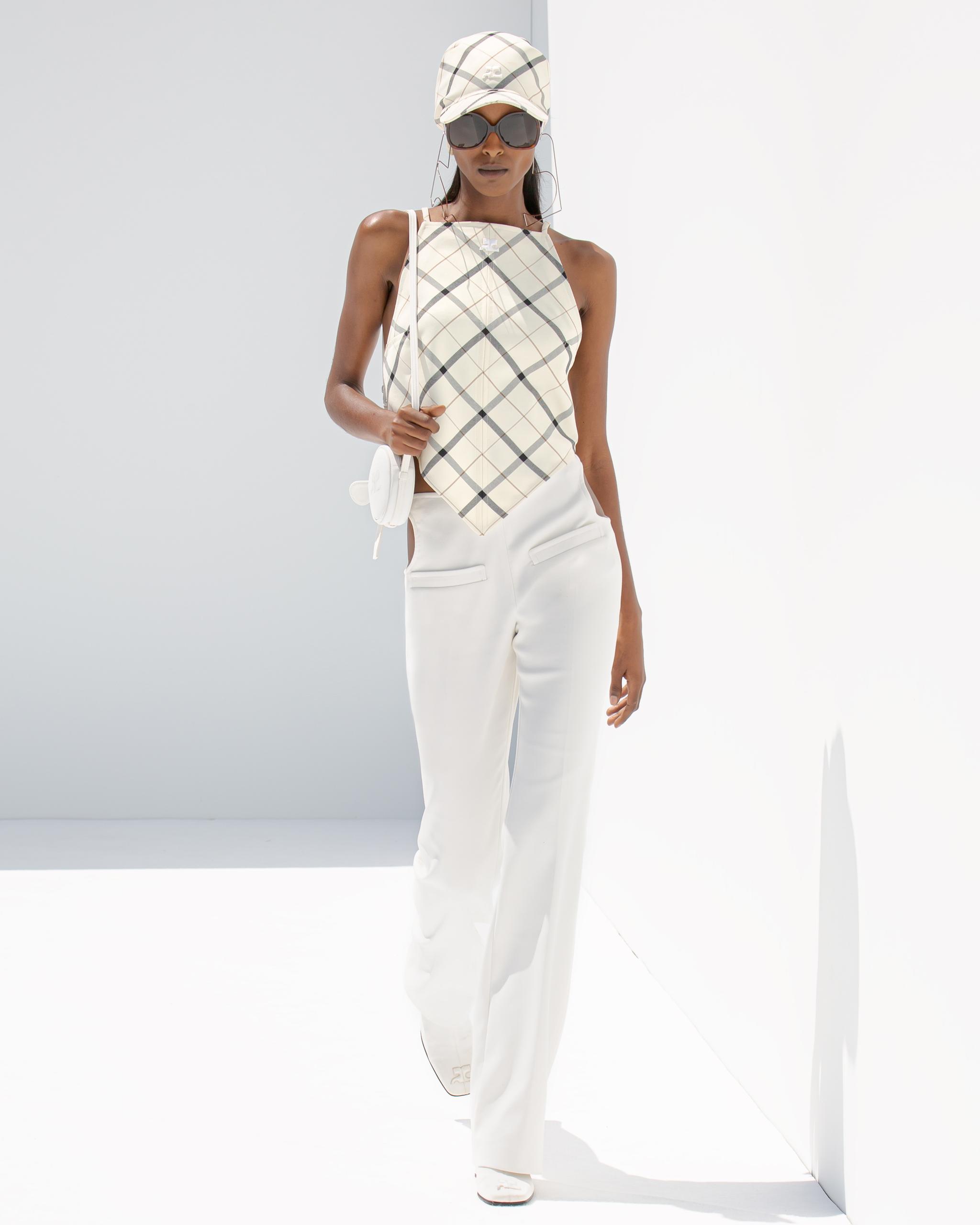 Fashion model showcasing elegant white trousers and a plaid top for Courrèges on an ecommerce platform.