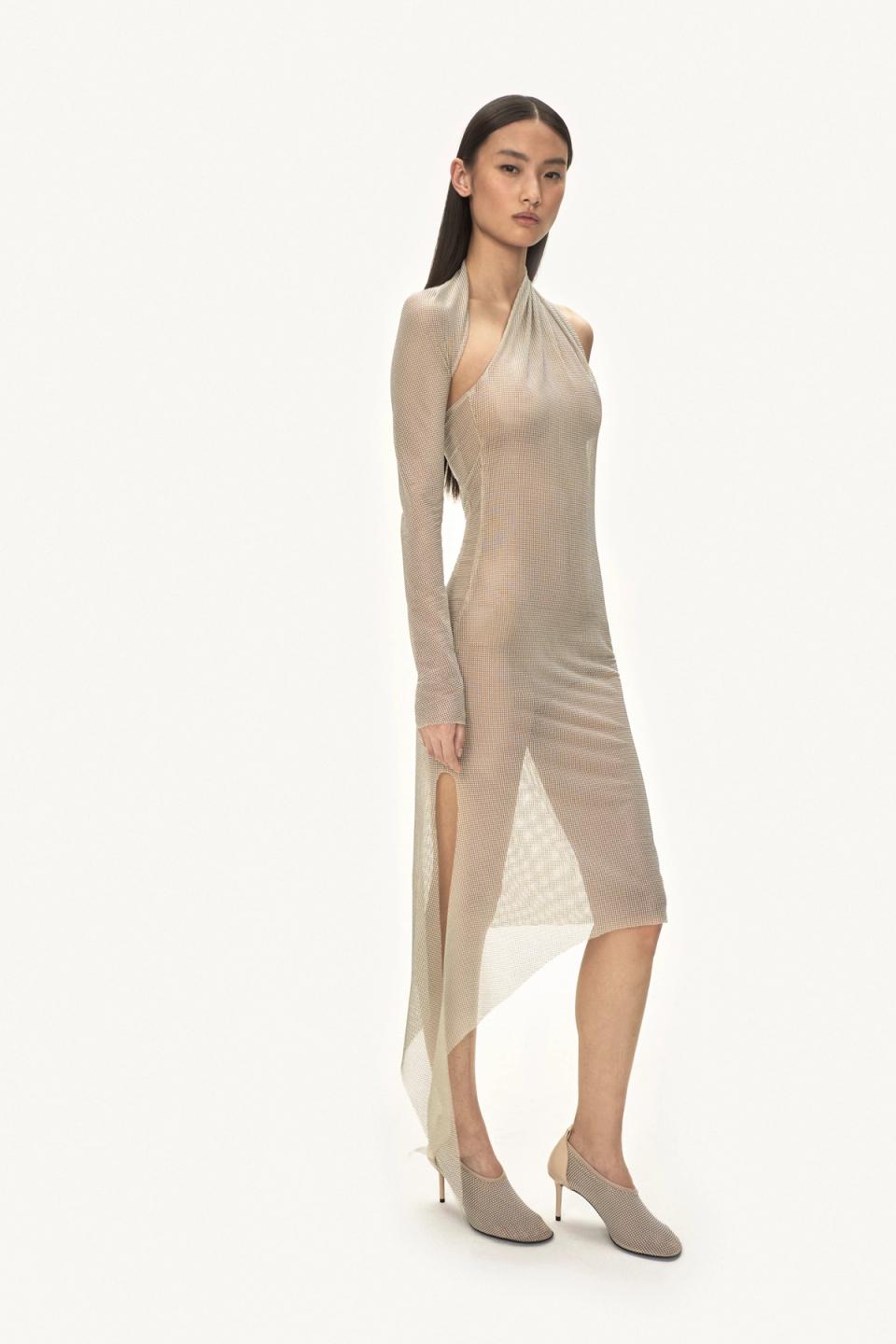 Elegant model in a shimmering Courrèges dress with side slit, perfect for fashion-forward looks.