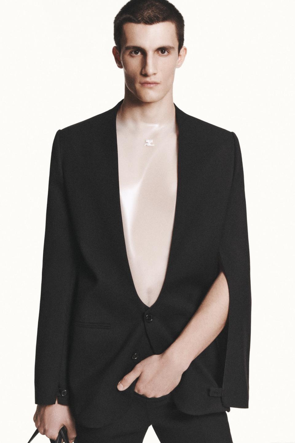 Elegant male model wearing a sleek black blazer with deep V neckline, featured on Courrèges ecommerce site.