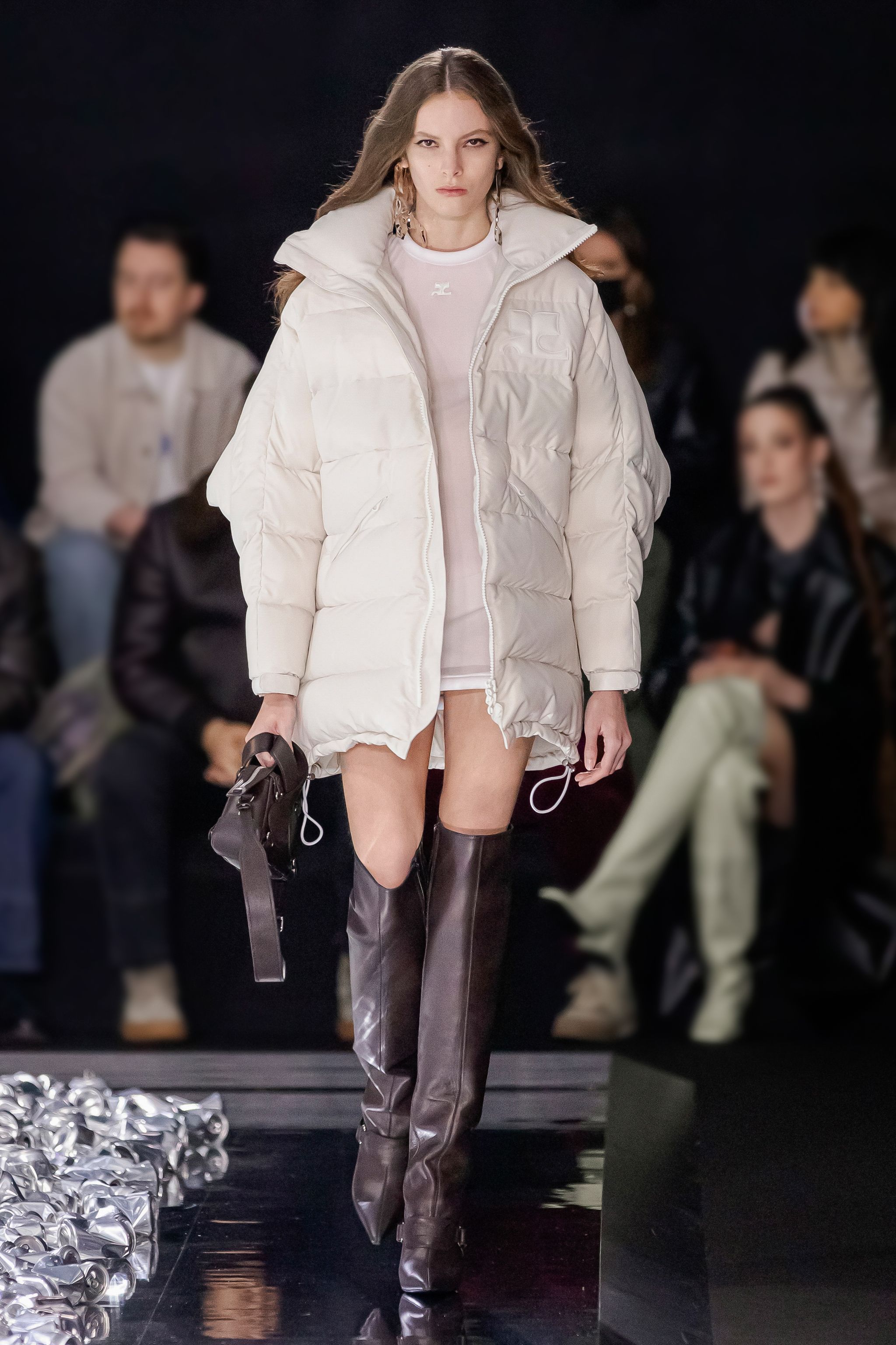 Elegant white puffer jacket and thigh-high leather boots showcased on a fashion runway for Courrèges.
