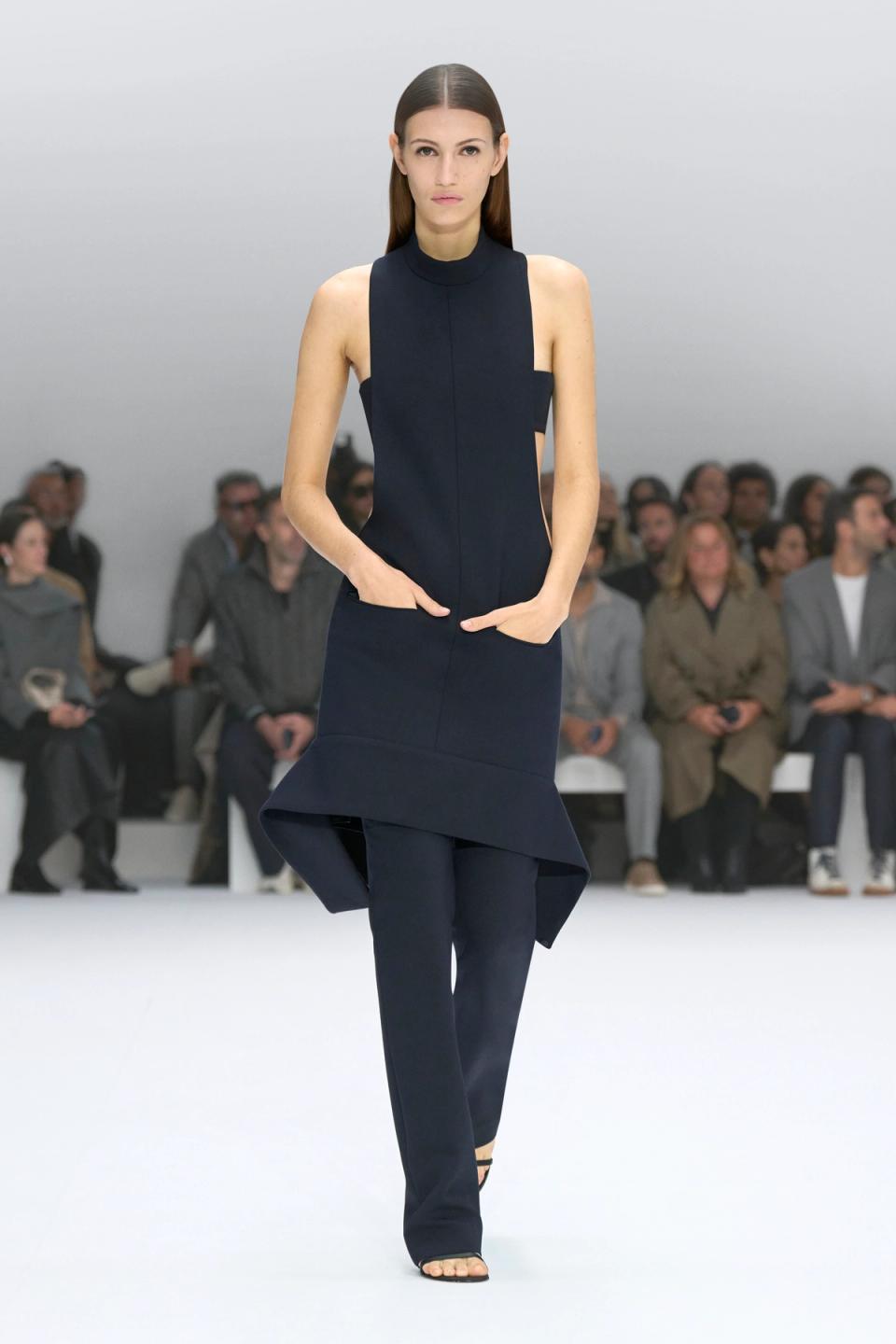 Elegant navy dress with cut-outs by Courrèges showcased on a runway at a fashion show.