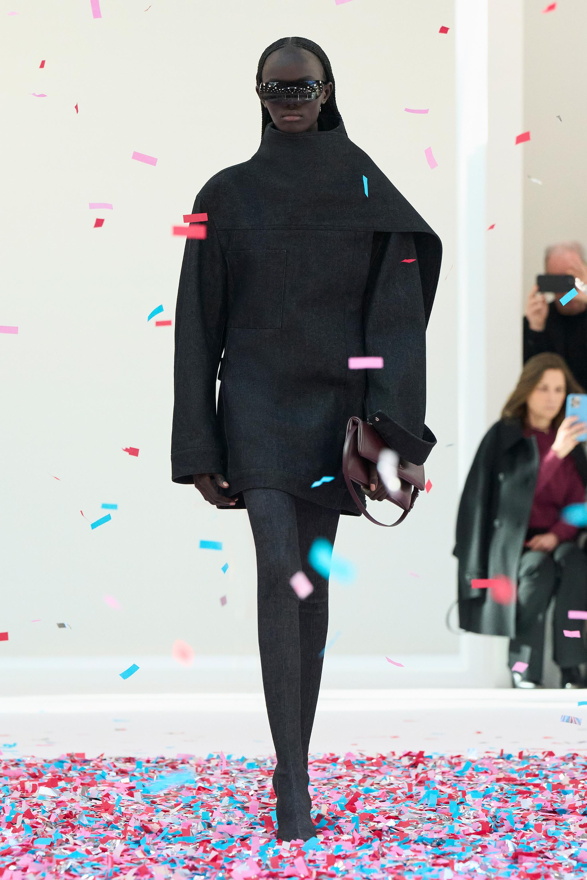 Elegant black fashion ensemble by Courrèges showcased on runway with confetti.