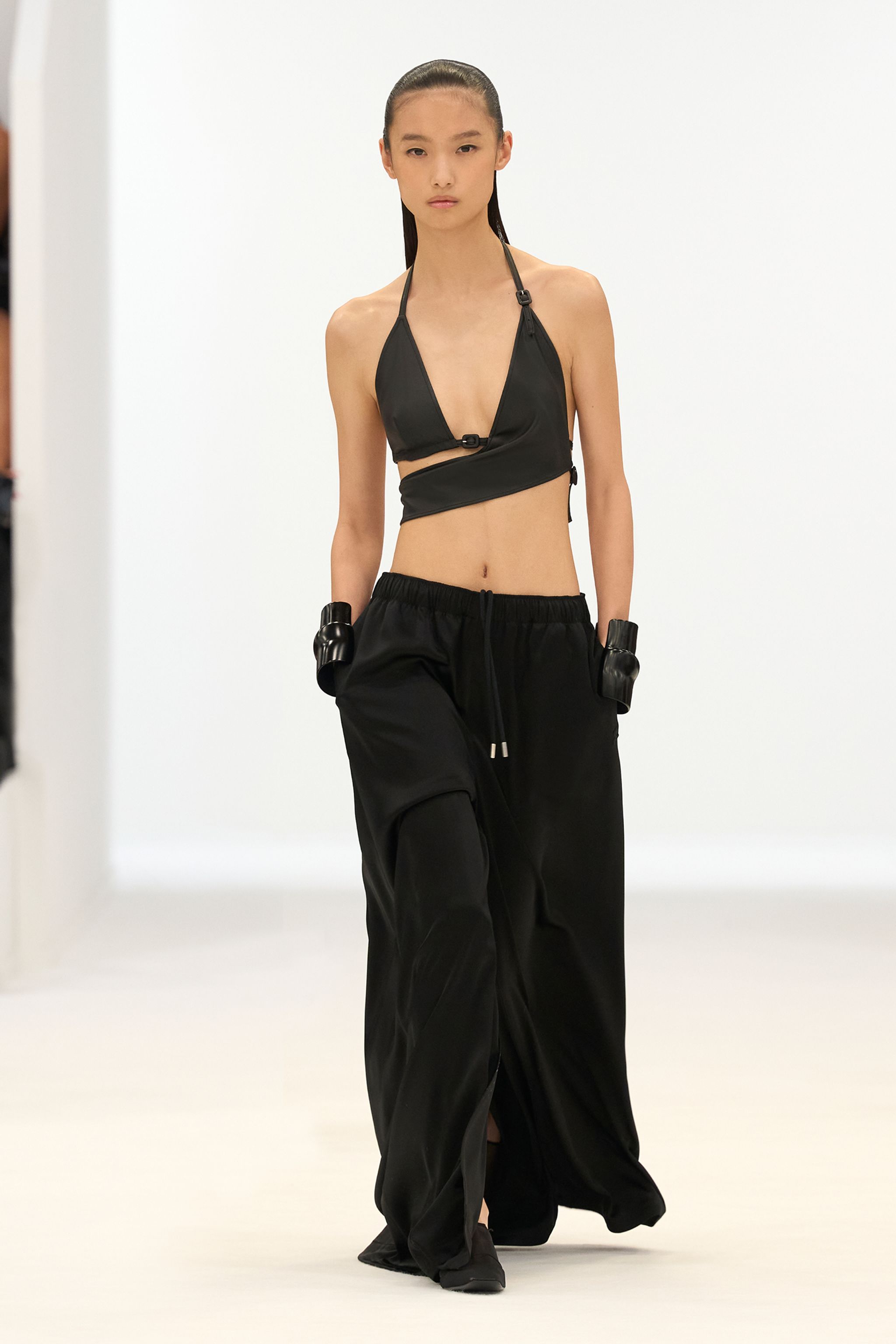 Elegant black crop top and wide-leg trousers by Courrèges, showcased on the runway.