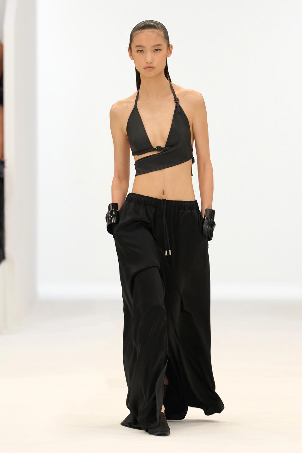 Elegant black crop top and wide-leg trousers by Courrèges, showcased on the runway.
