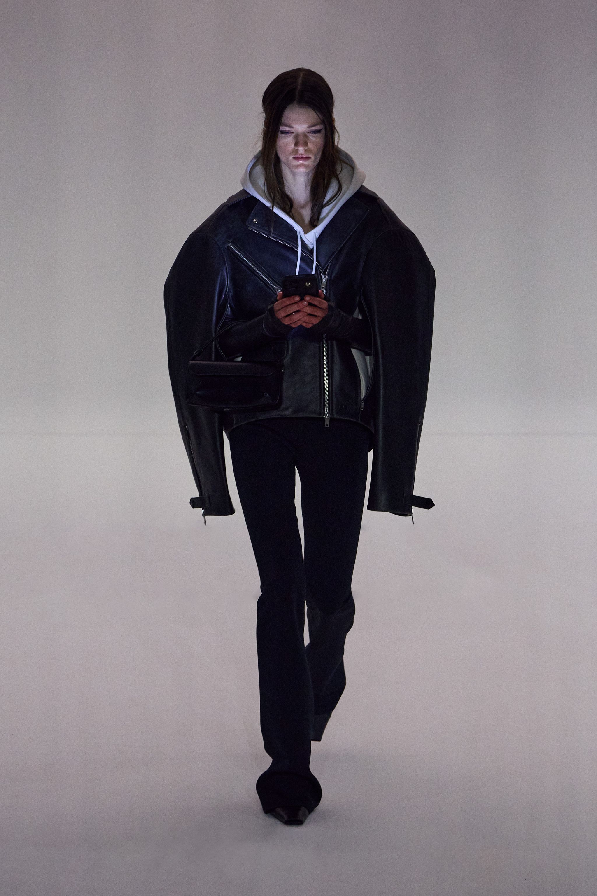 Elegant model in black leather jacket and hoodie showcasing Courrèges fashion for ecommerce.