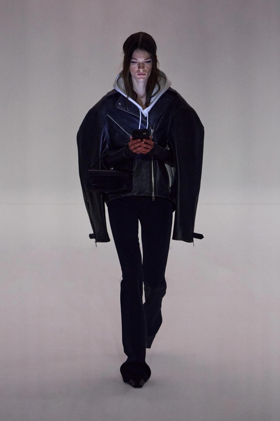 Elegant model in black leather jacket and hoodie showcasing Courrèges fashion for ecommerce.