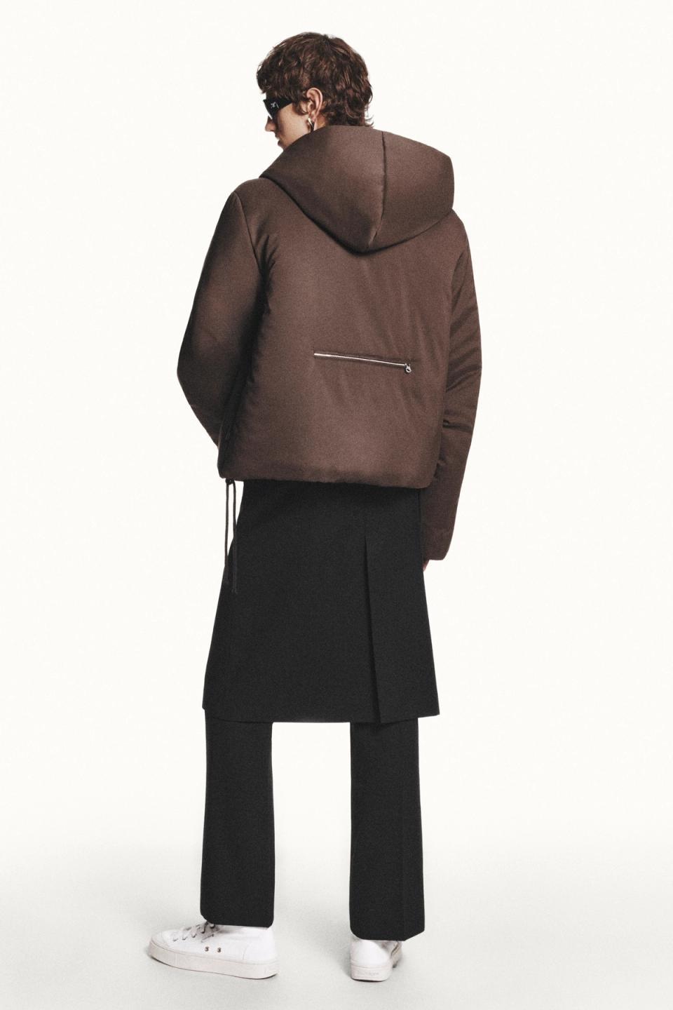 Elegant Courrèges fashion featuring a brown hooded puffer jacket and black trousers.