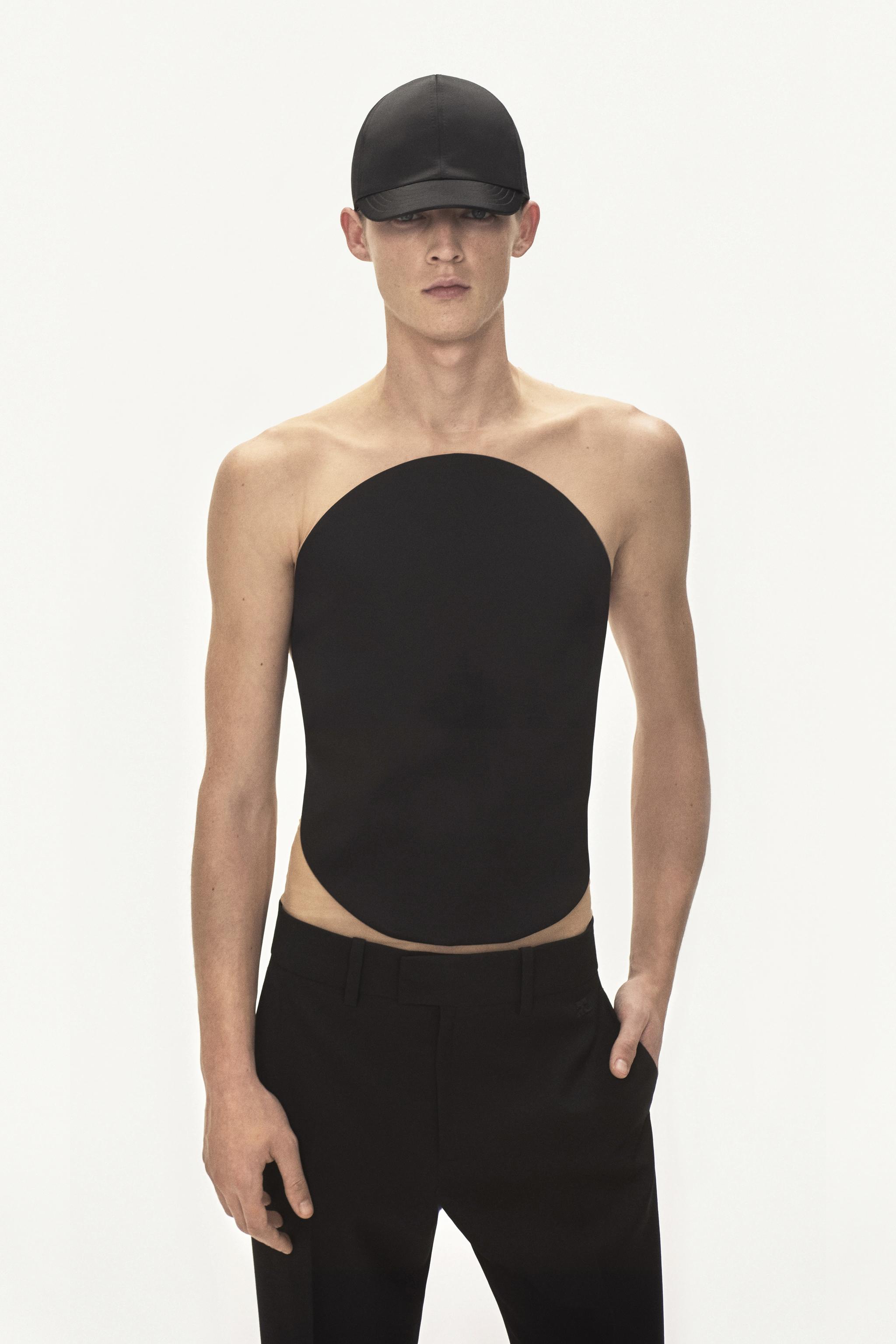 Haut de mode noir élégant au design épuré, porté avec un pantalon noir pour Courrèges.