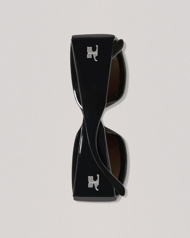 Lunettes de soleil noires élégantes avec un design torsadé unique et logo Courrèges pour un style moderne.