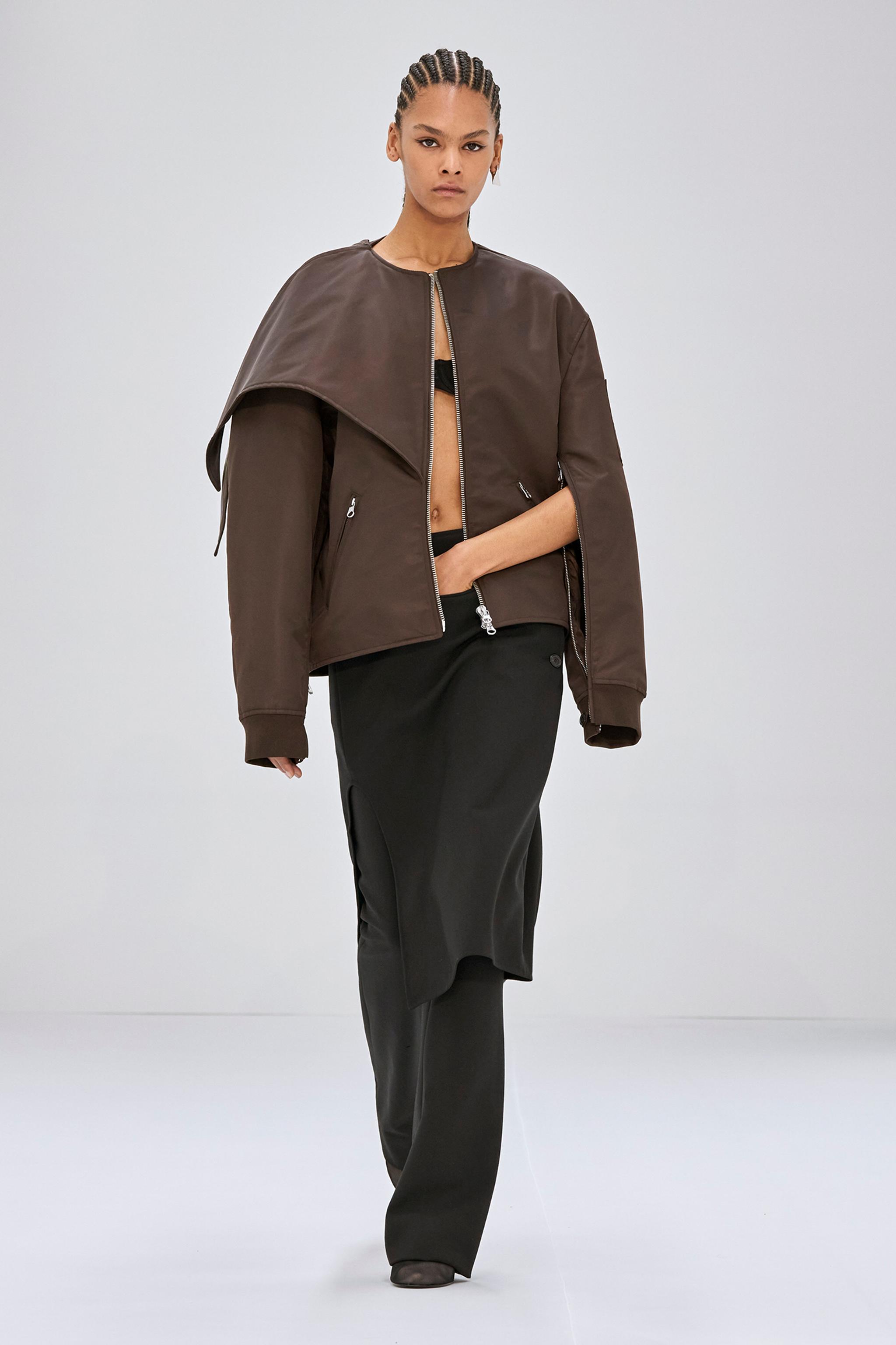 Mode féminine élégante de Courrèges avec une veste en cuir marron et une jupe noire assortie.