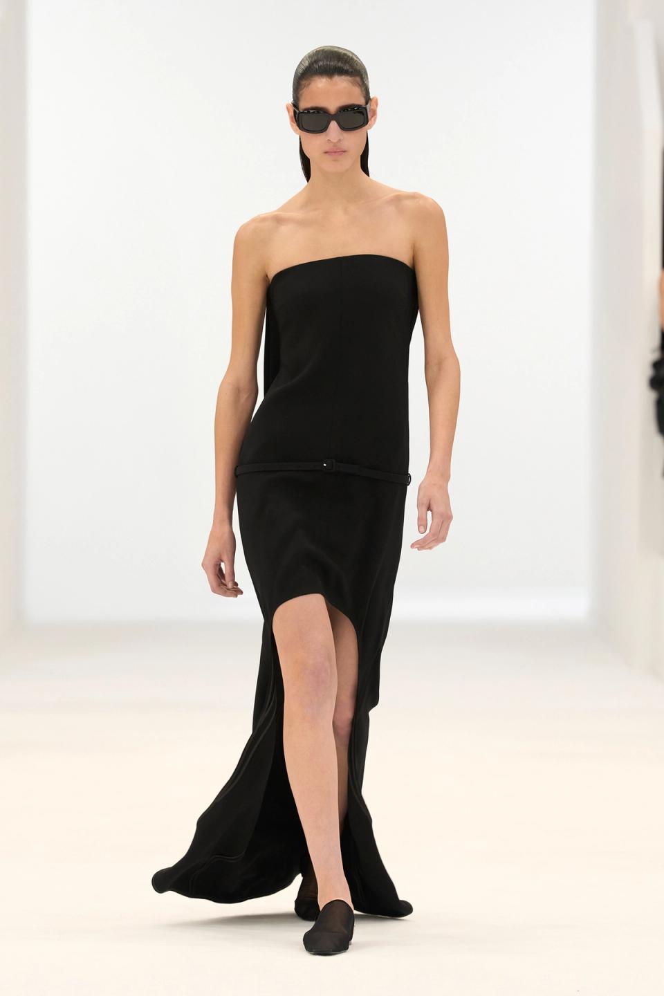 Elegant black strapless dress with a slit, modeled for Courrèges on an ecommerce site.