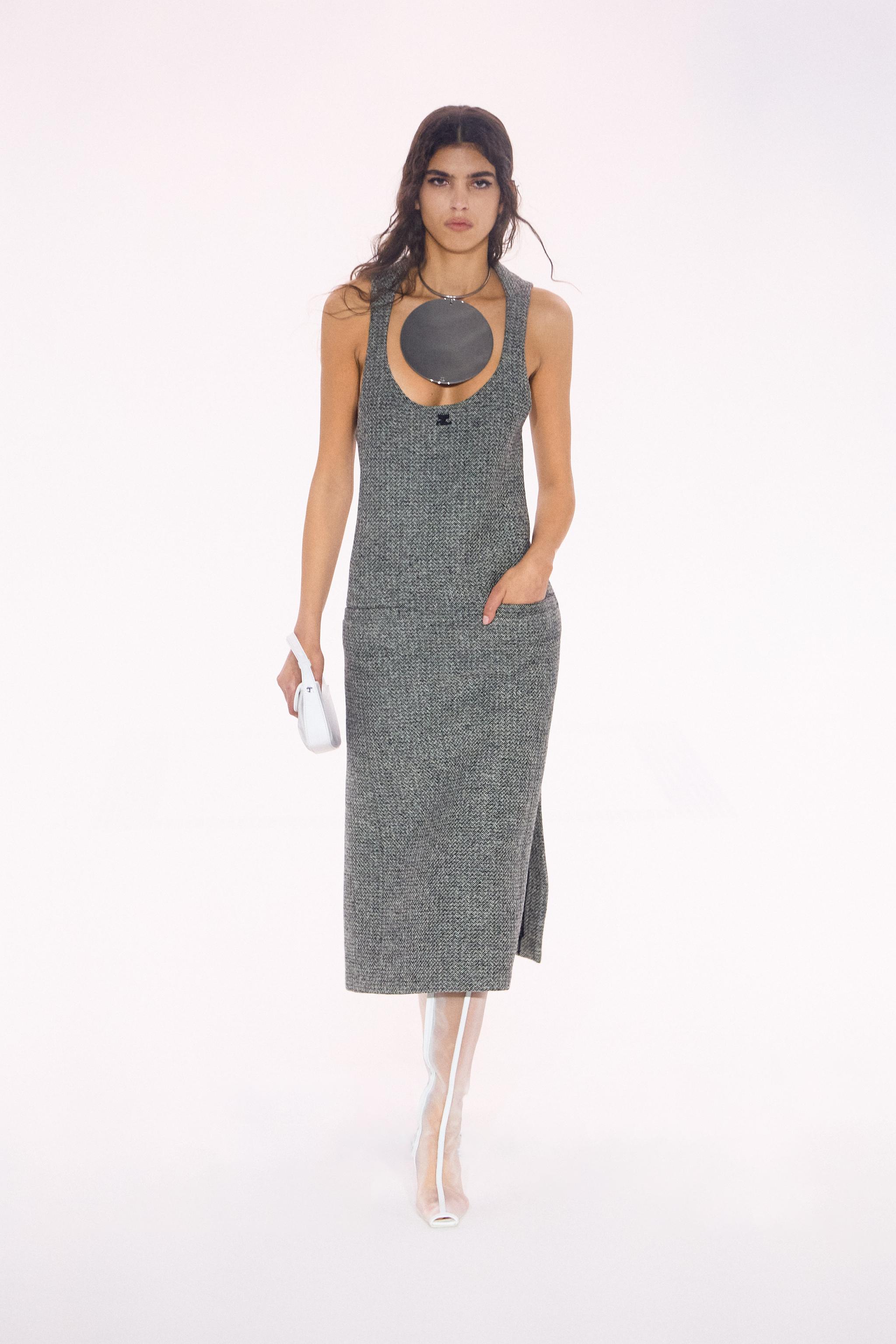 Elegant model in gray dress showcasing Courrèges fashion brand on a minimalist white runway.