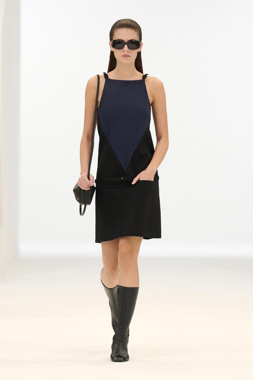 Elegantly styled model in Courrèges fashion with a sleek black and navy dress, sunglasses, and boots.