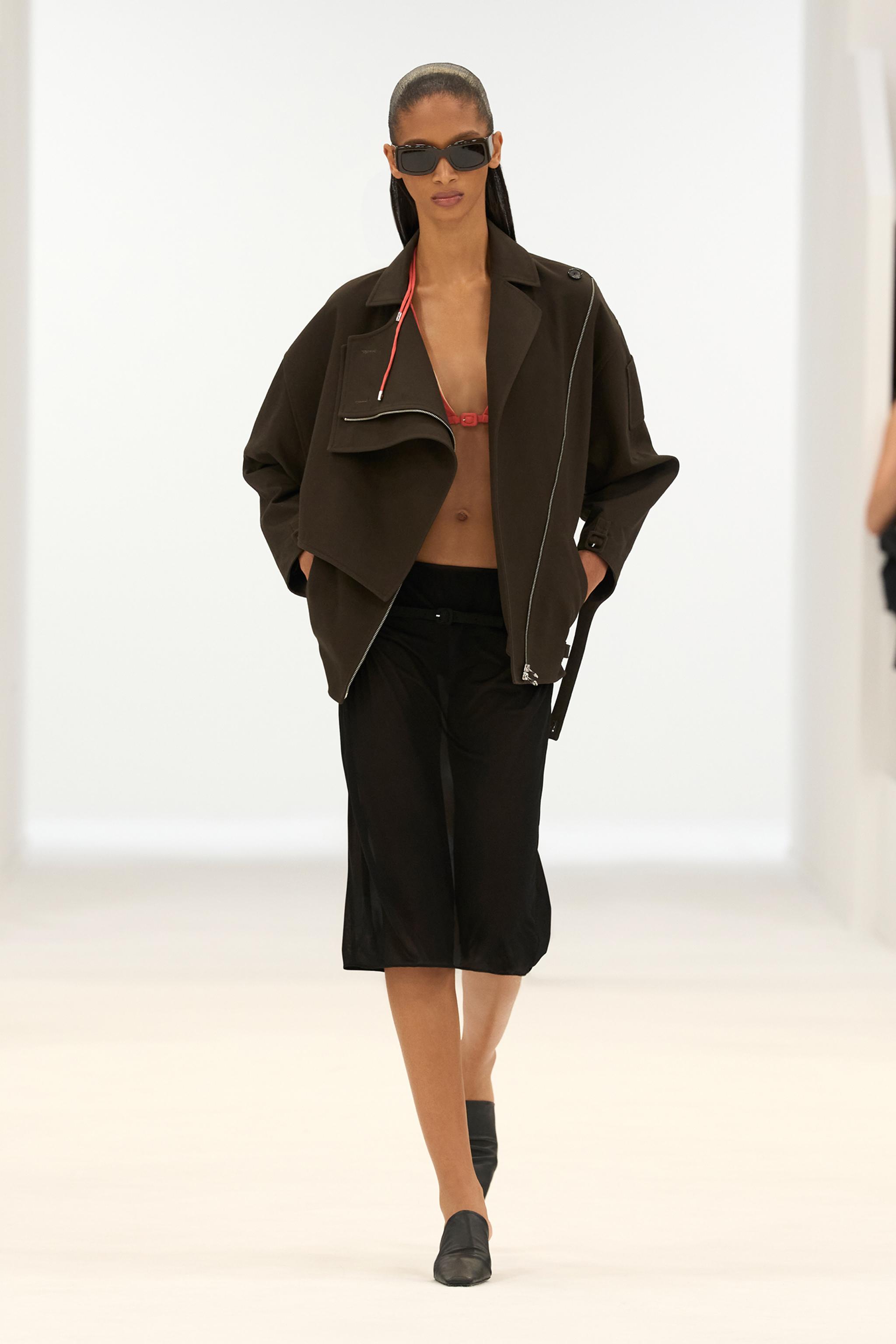Elegant Courrèges fashion model wearing a black jacket, sunglasses, and stylish black shoes.