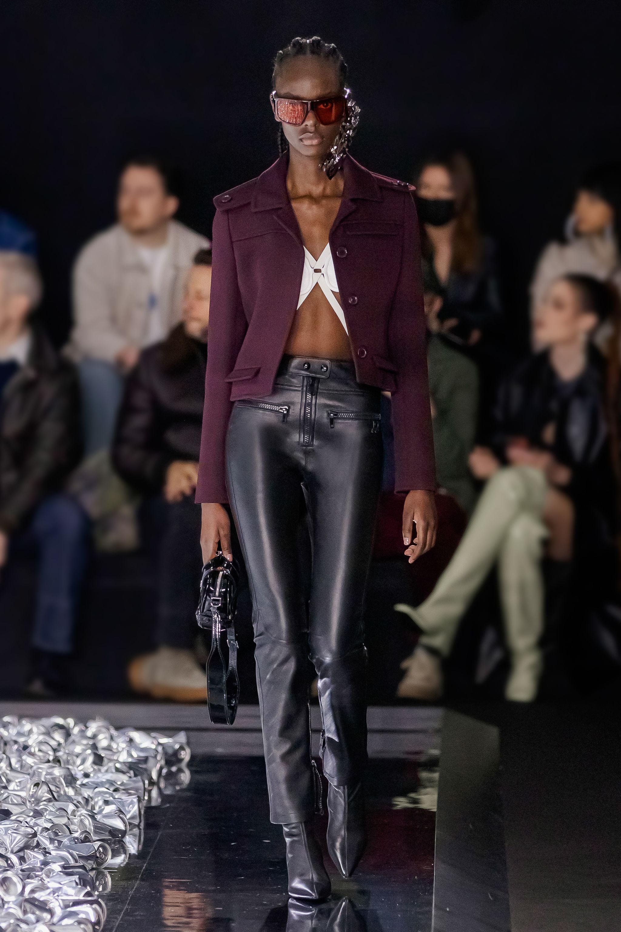 Elegant fashion runway model wearing Courrèges collection, stylish leather pants and modern accessories.