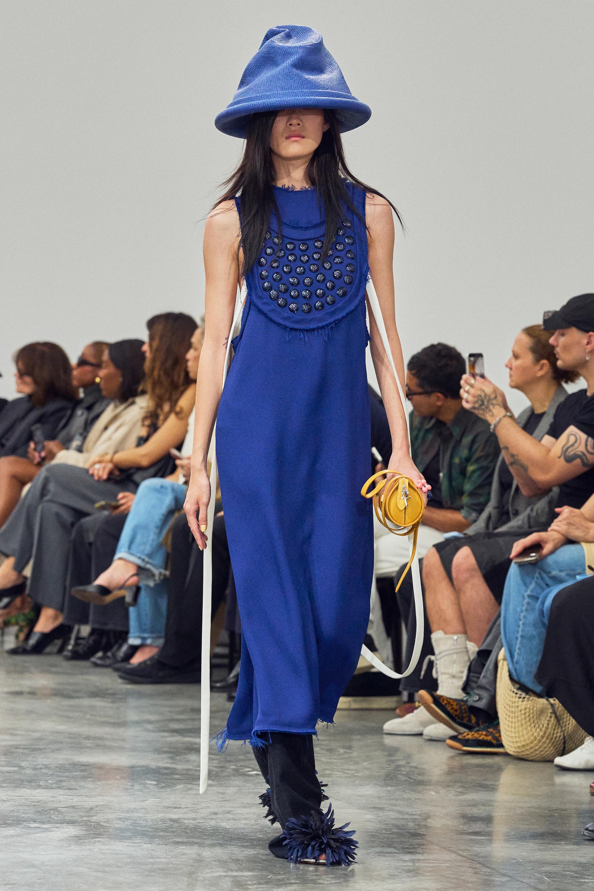 Elegant model in vibrant blue Courrèges fashion on runway with stylish audience.
