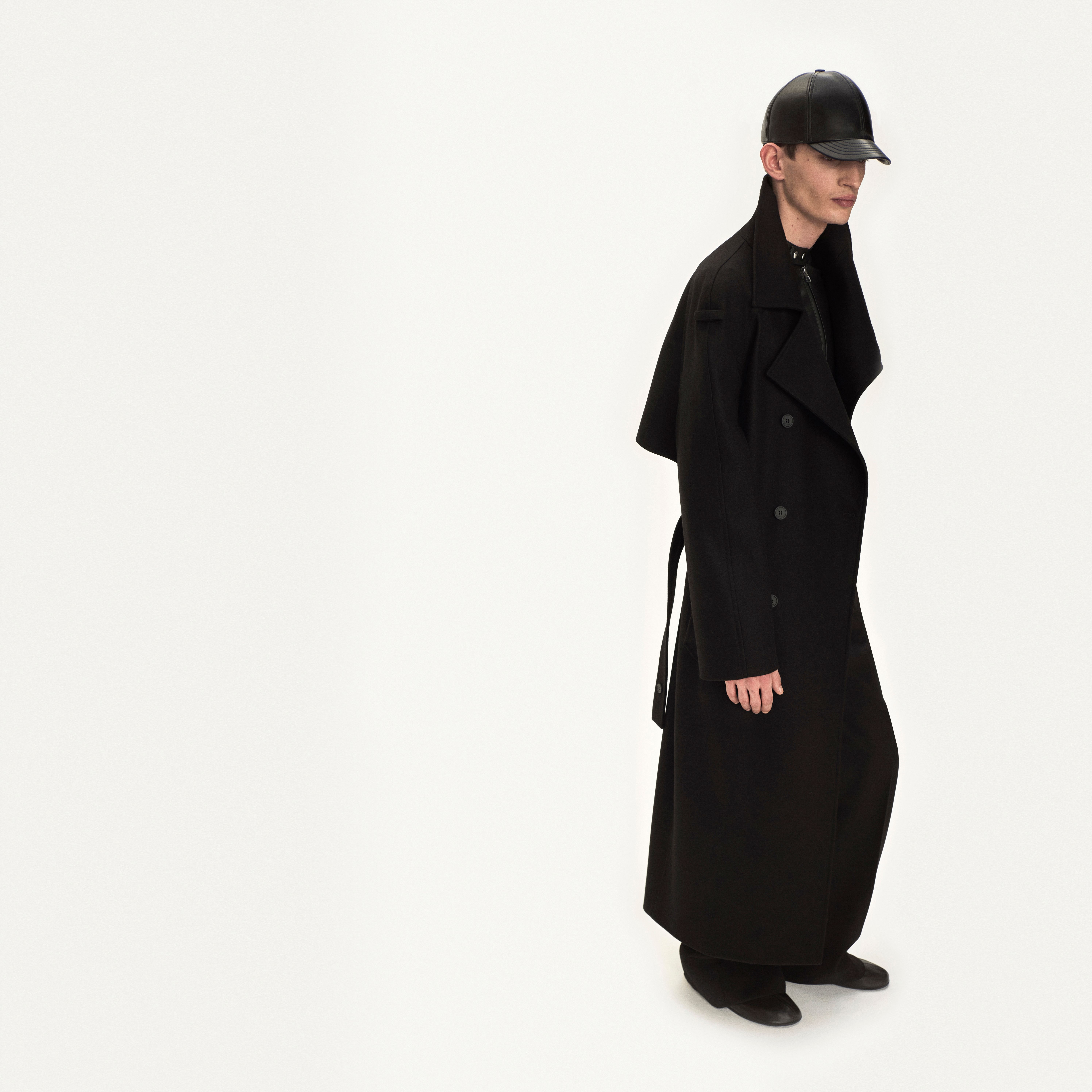Elegant black trench coat and leather cap by Courrèges, perfect for modern fashion statements.