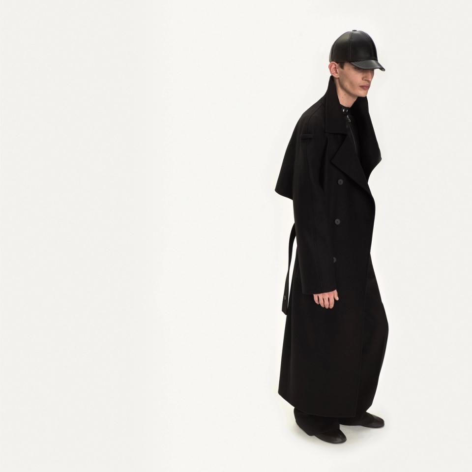 Elegant black trench coat and leather cap by Courrèges, perfect for modern fashion statements.